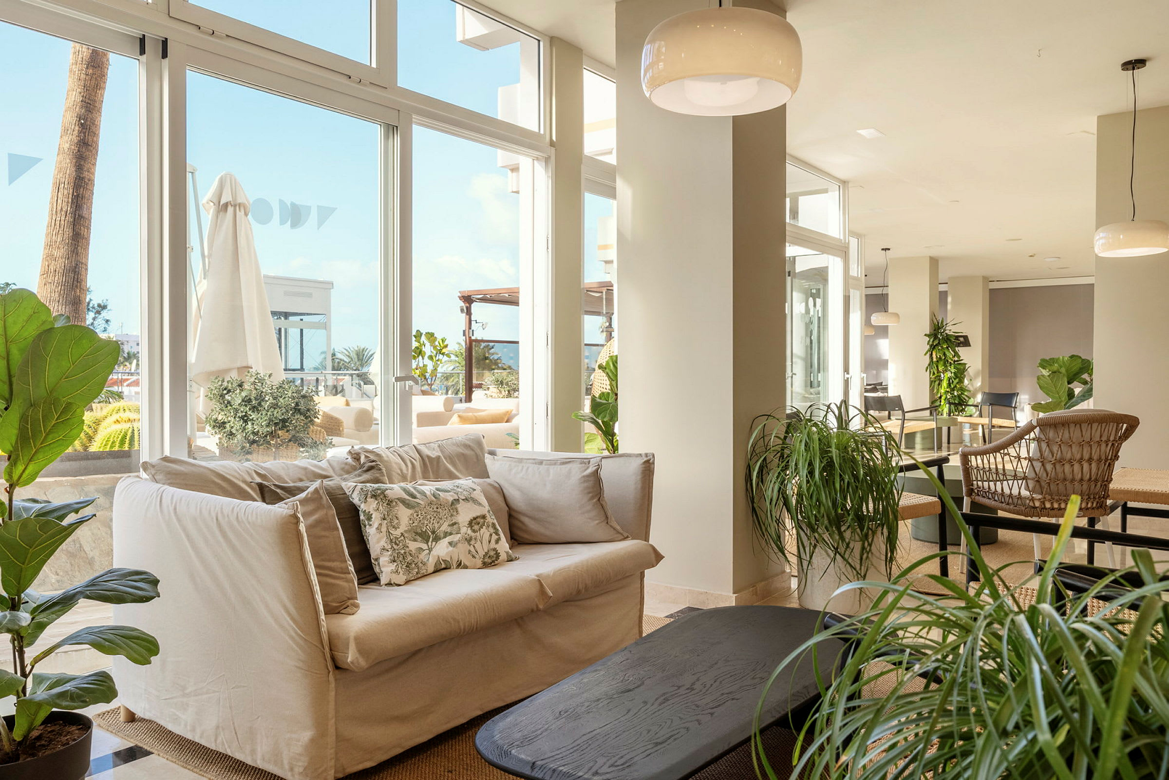 Et lyst og åpent innendørsområde med moderne innredning, komfortable møbler og store vinduer med utsikt mot en terrasse. (AI-generert tekst)