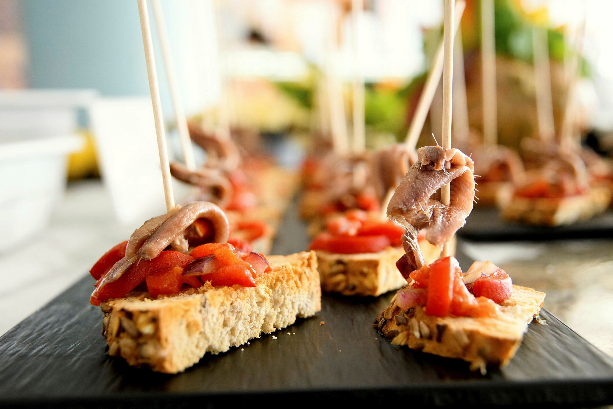 Nærbilde av små brødskiver toppet med ansjos og paprika. (AI-generert tekst)