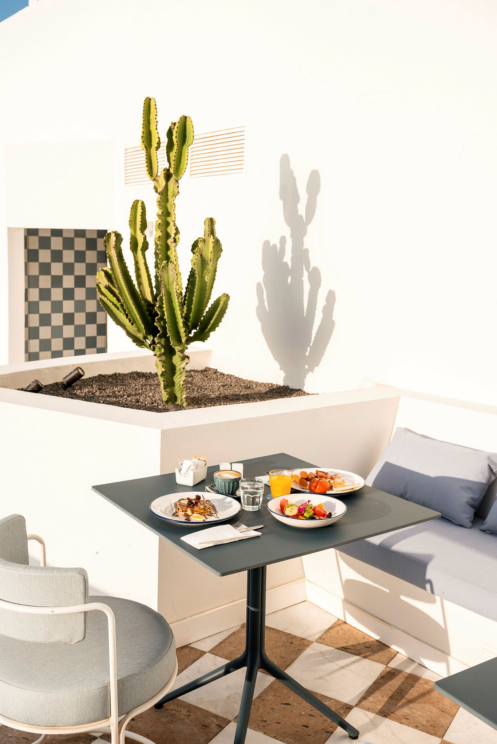 Et bord med frokostoppsett på en terrasse med en kaktus i bakgrunnen. (AI-generert tekst)