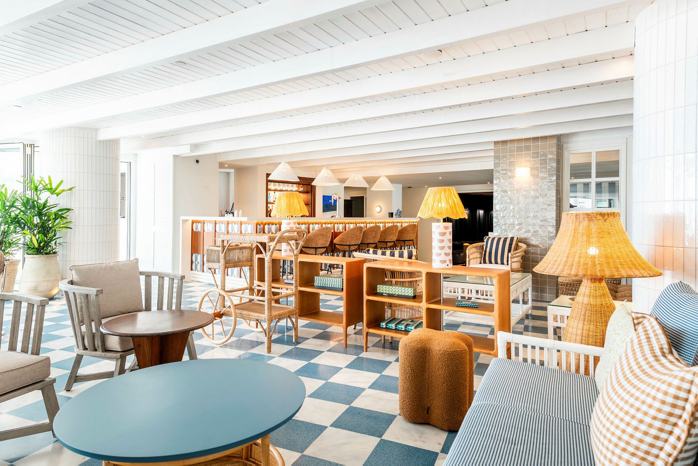 Interiør av en lys og elegant innredet salong med sofaer, lenestoler, lamper og et rutete gulv i blått og hvitt. (AI-generert tekst)