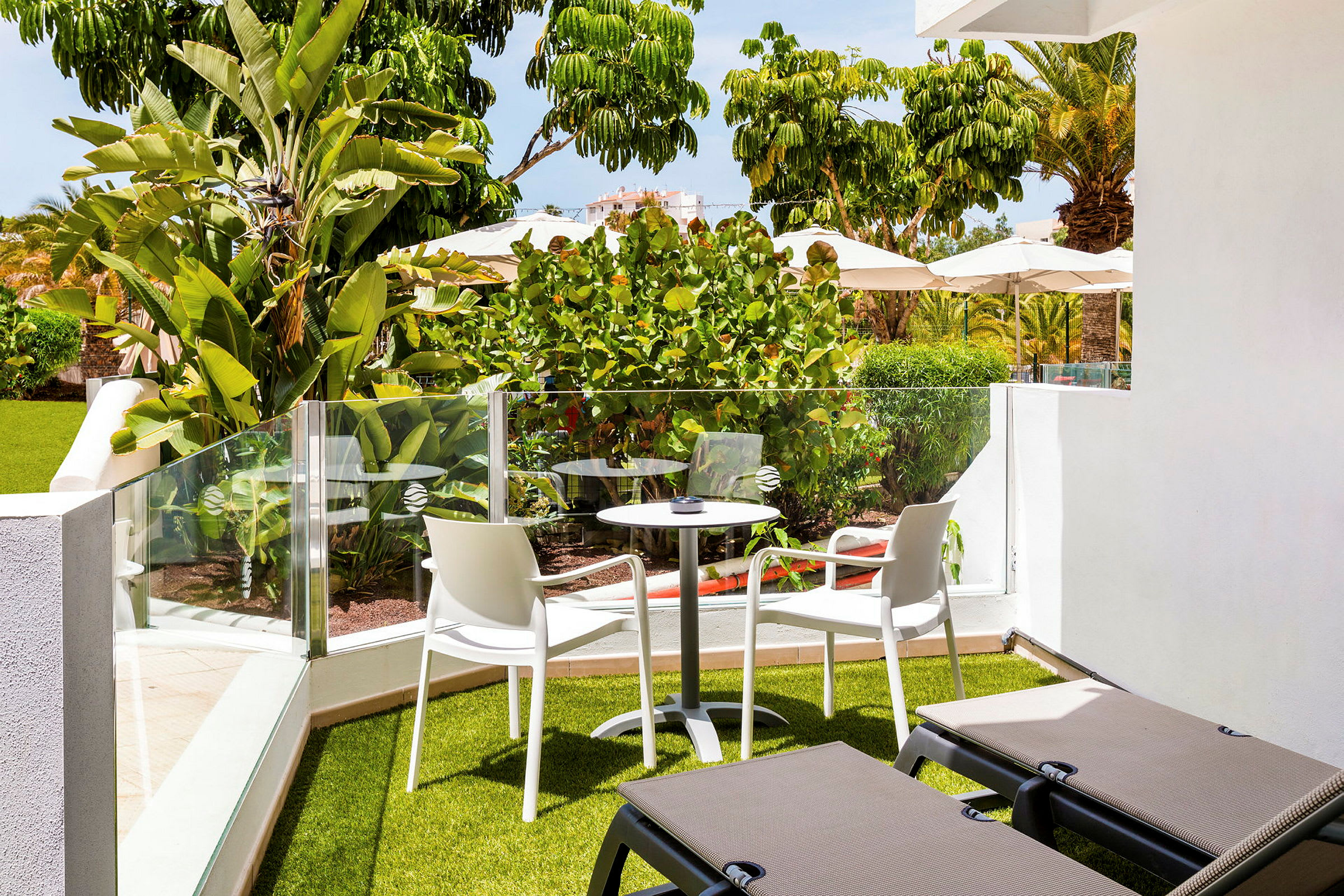Hageterrasse med grøntområder, utemøbler og solsenger. (AI-generert tekst)
