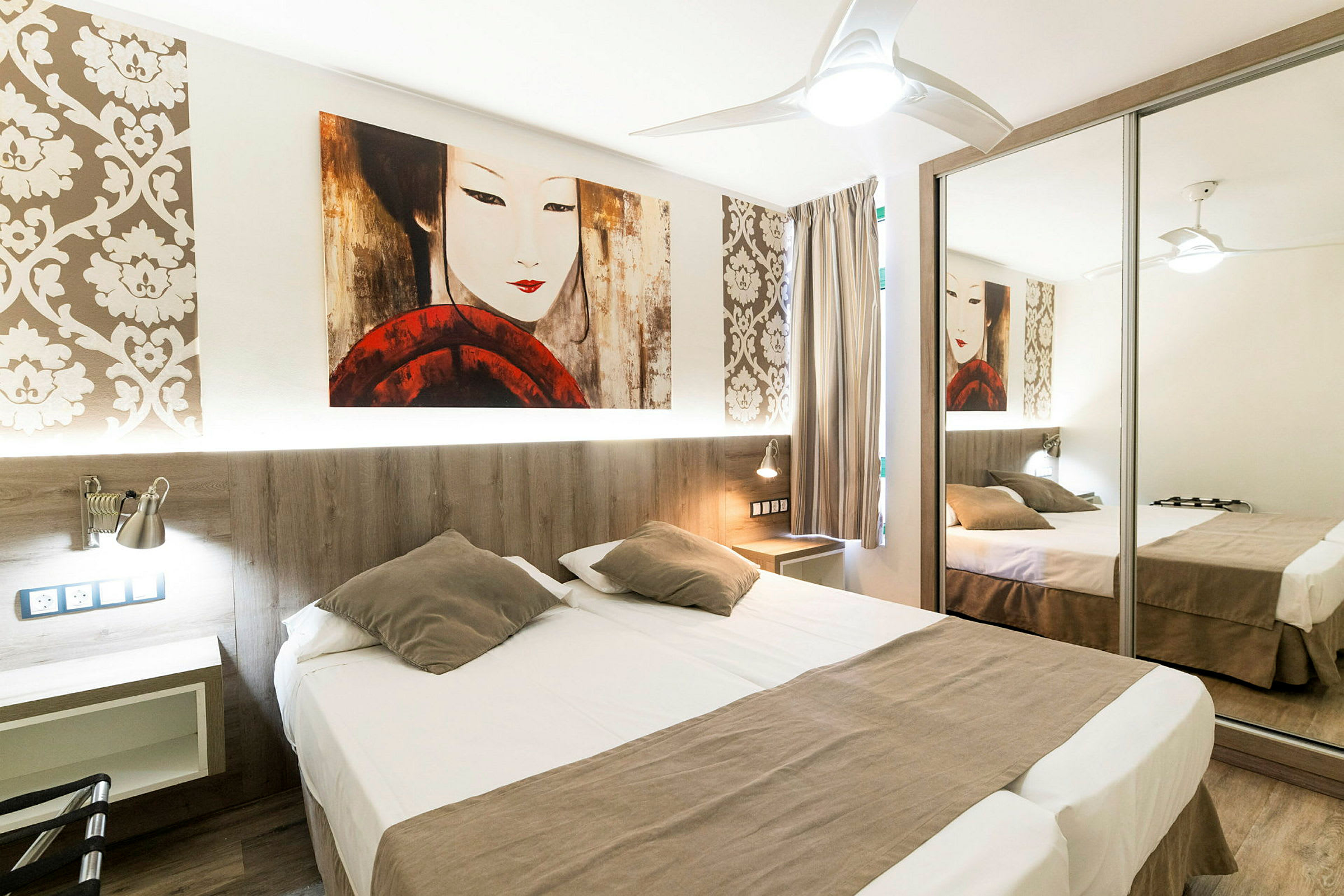 Et hotellrom med en dobbeltseng, speilgarderobe og dekorativ tapet. (AI-generert tekst)