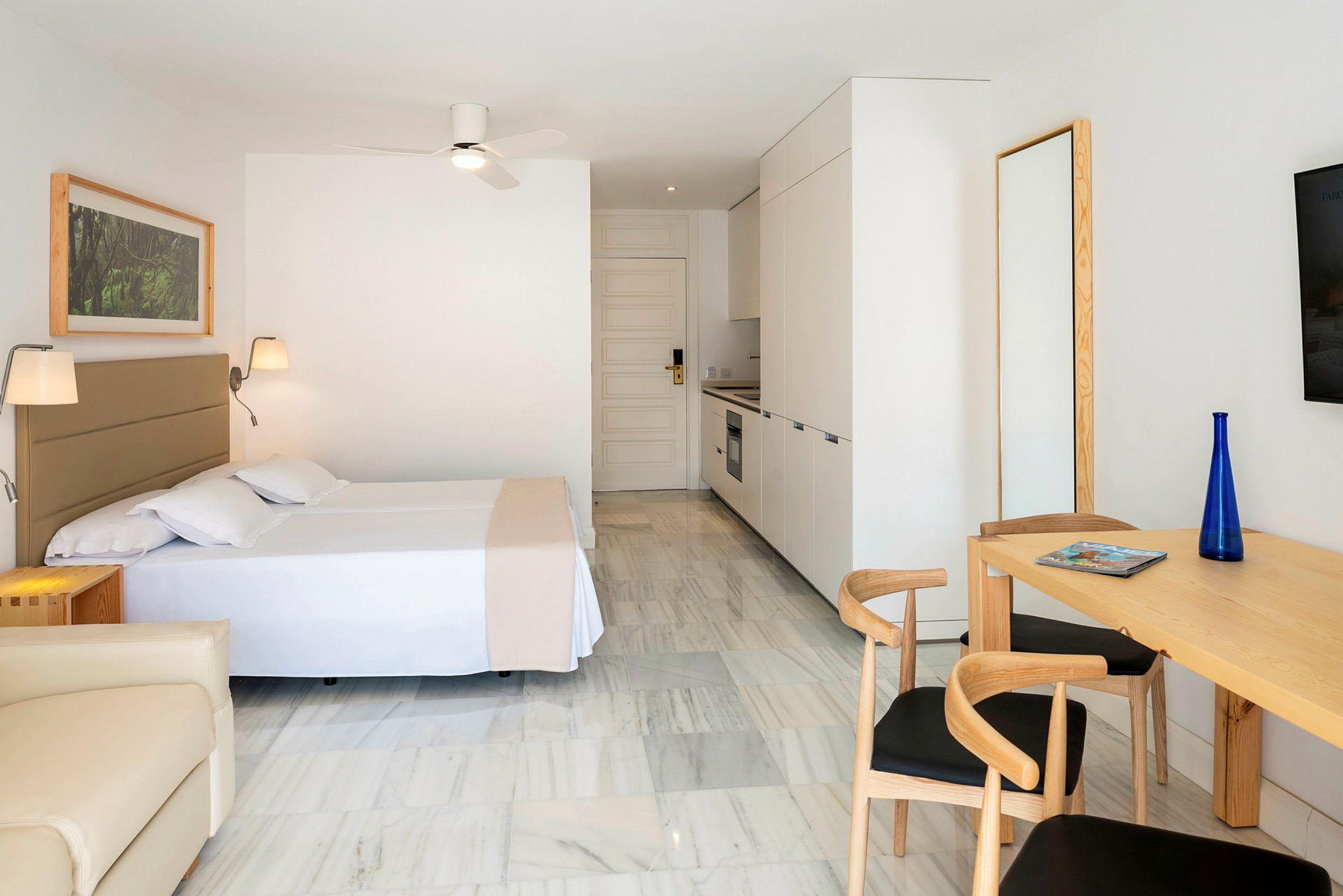 Moderne innredet hotellrom med kjøkkenkrok og spisebord. (AI-generert tekst)