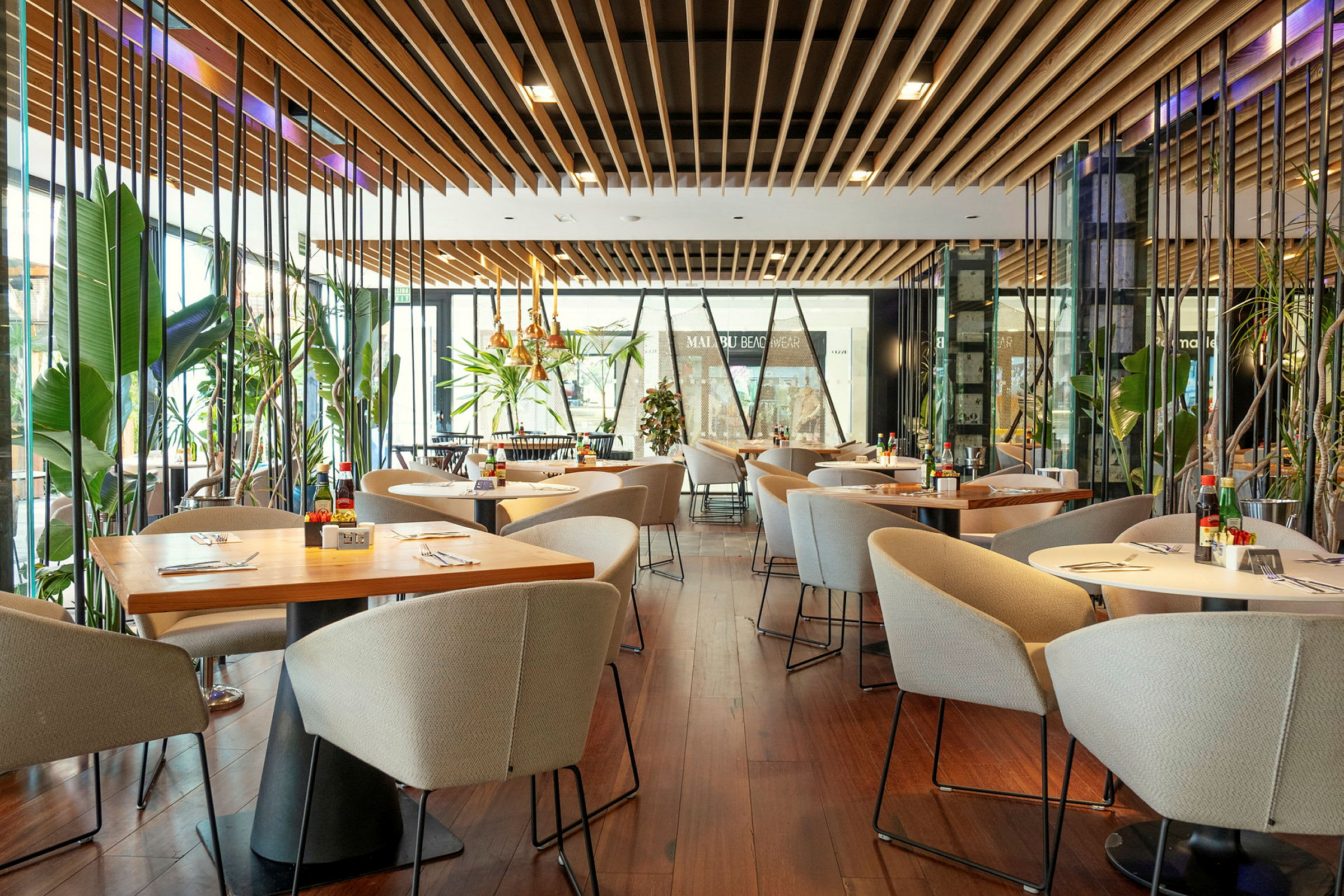 Moderne restaurant med bord, stoler og frodige planter. (AI-generert tekst)