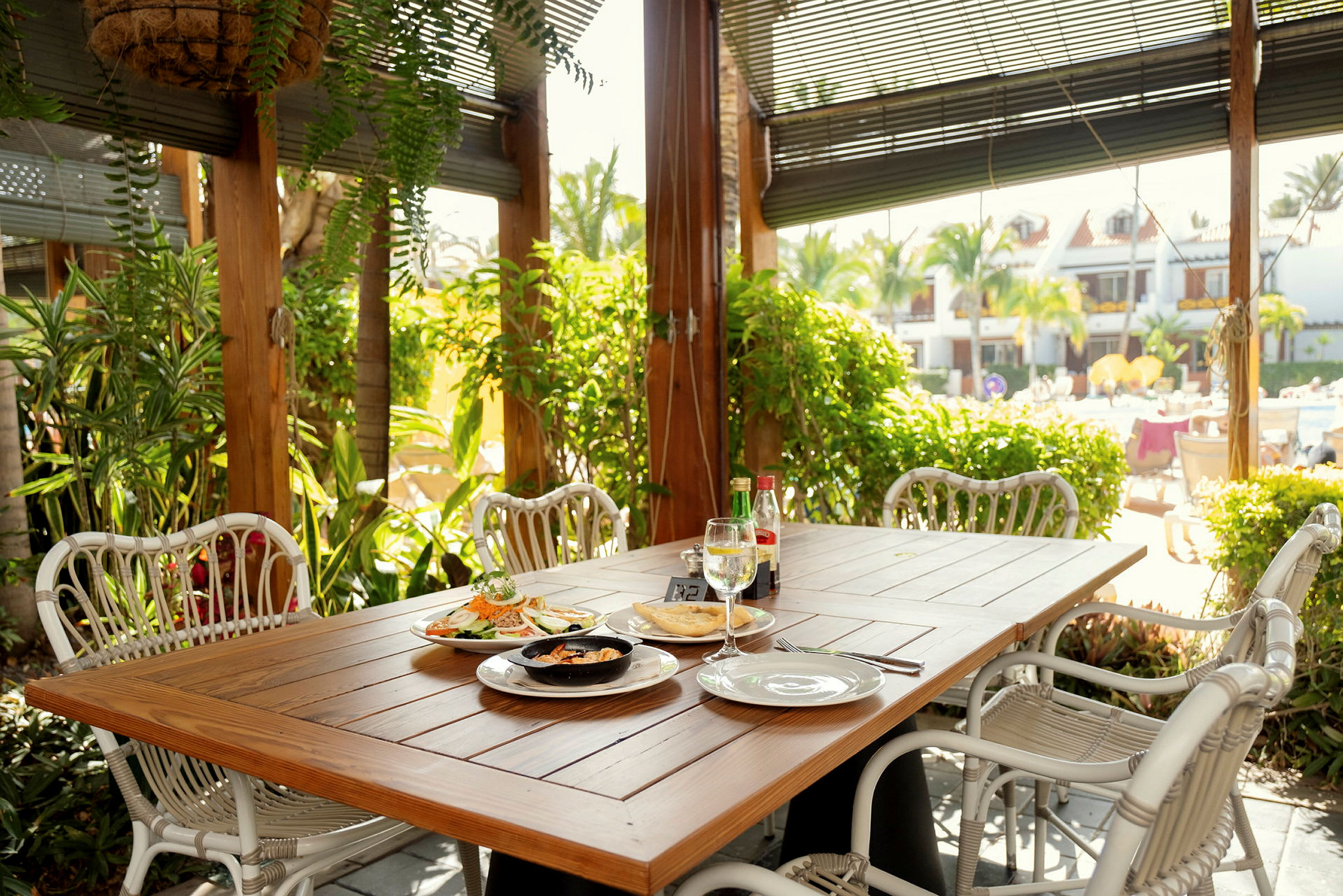 Et bord med mat plassert på en terrasse omgitt av grøntområder. (AI-generert tekst)