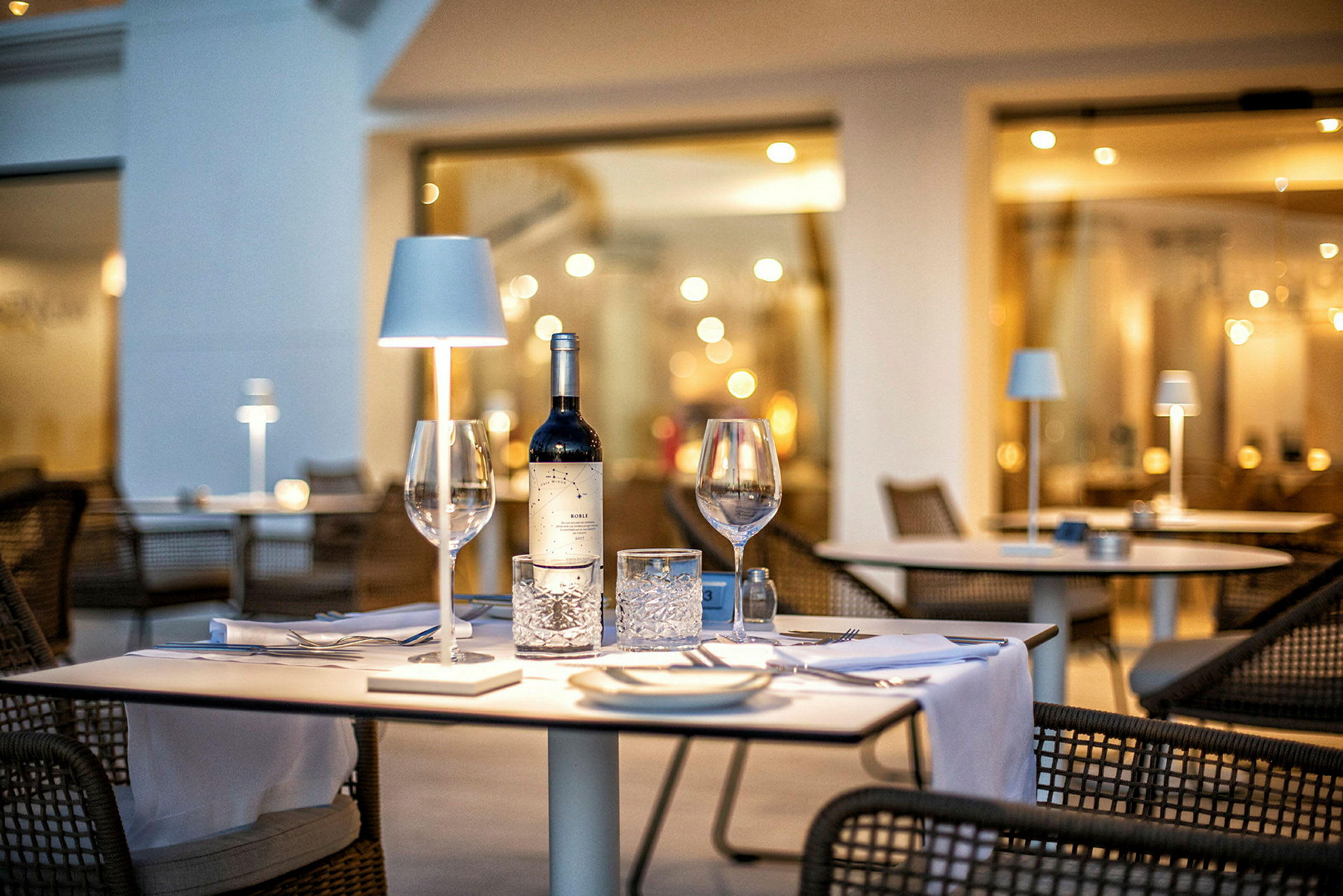 Et dekket bord med en vinflaske og glass på en restaurant. (AI-generert tekst)