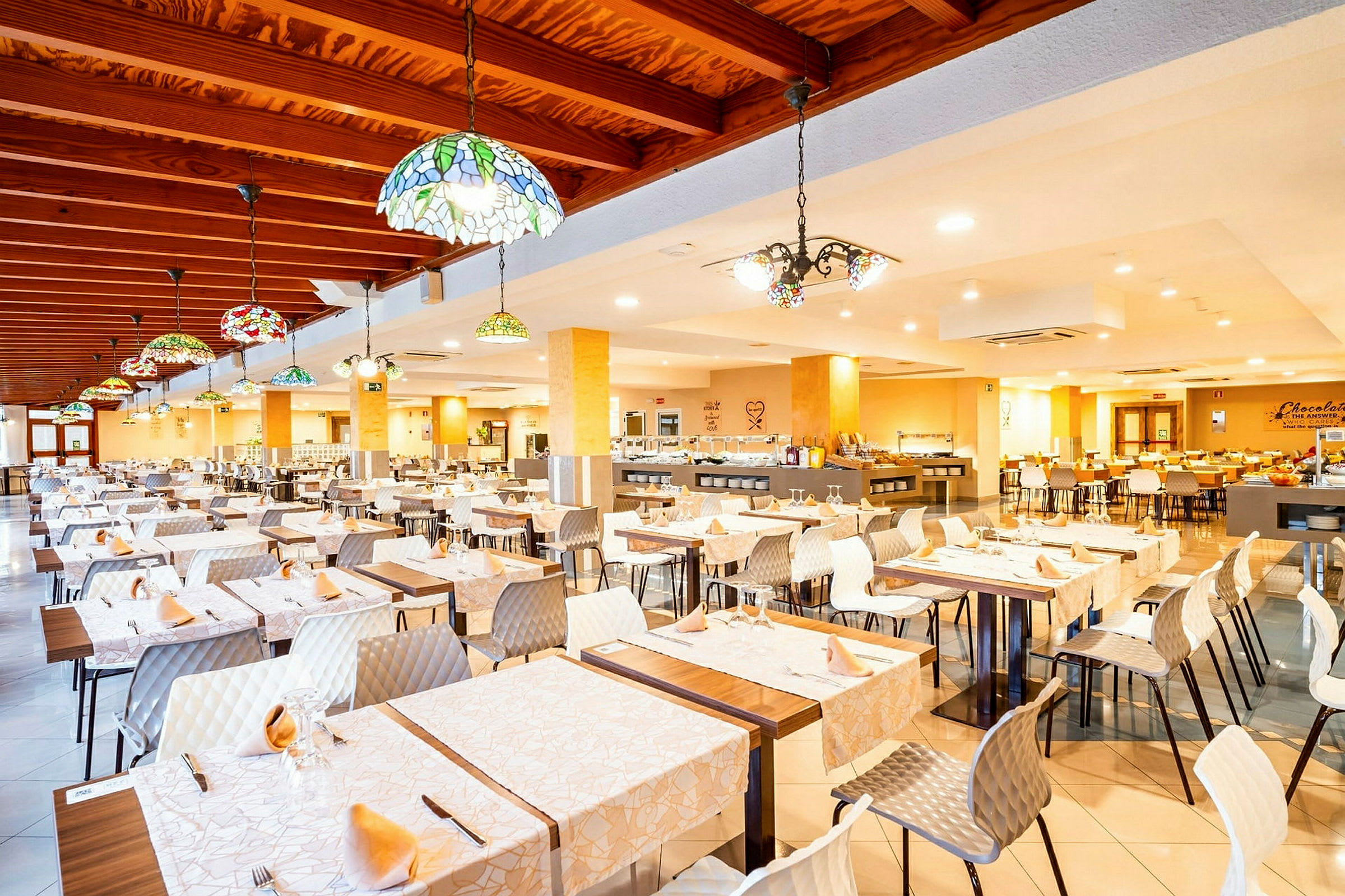 En romslig restaurant med dekkede bord og fargerike taklamper. (AI-generert tekst)