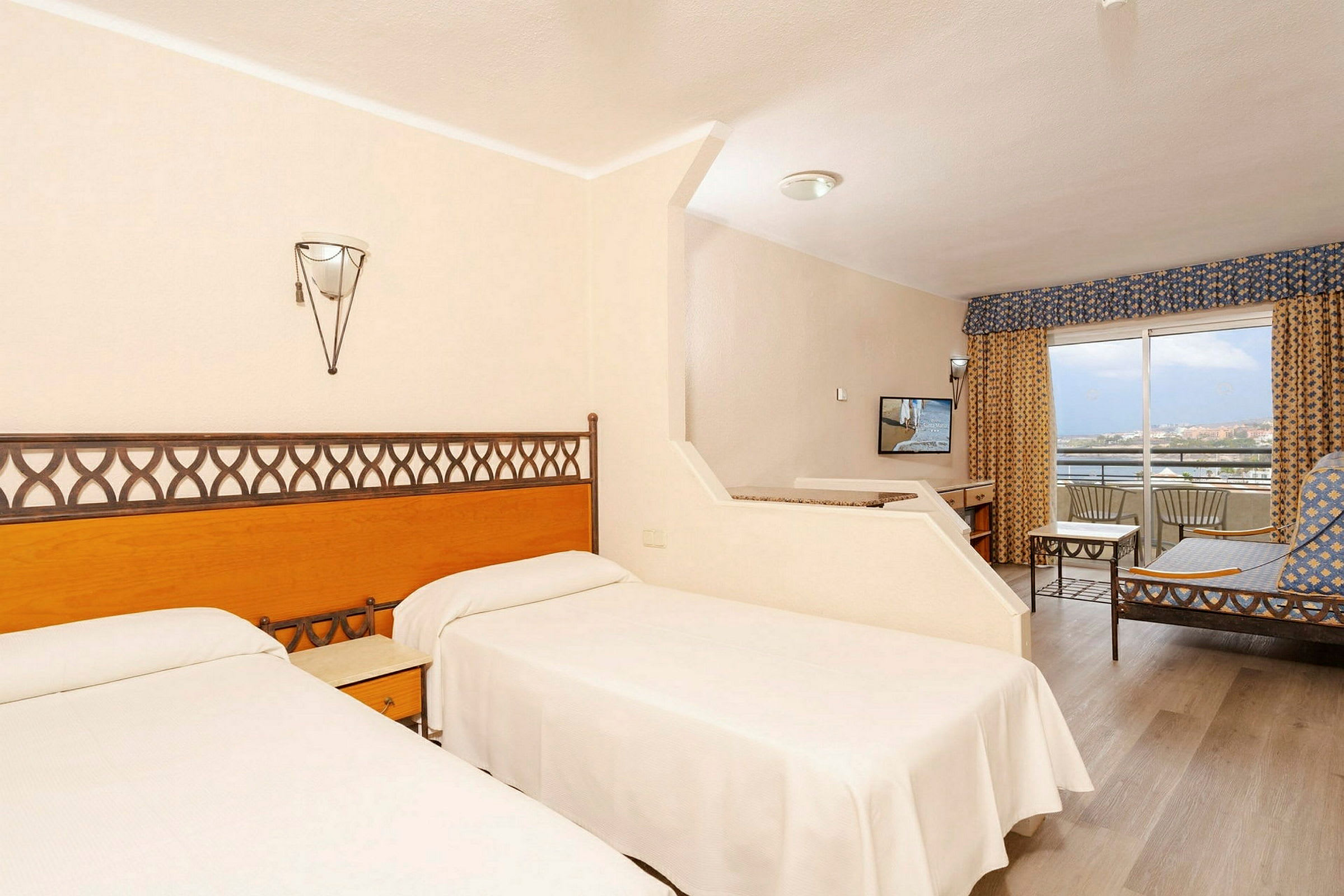 Hotellrom med to enkeltsenger, sittegruppe og balkong. (AI-generert tekst)