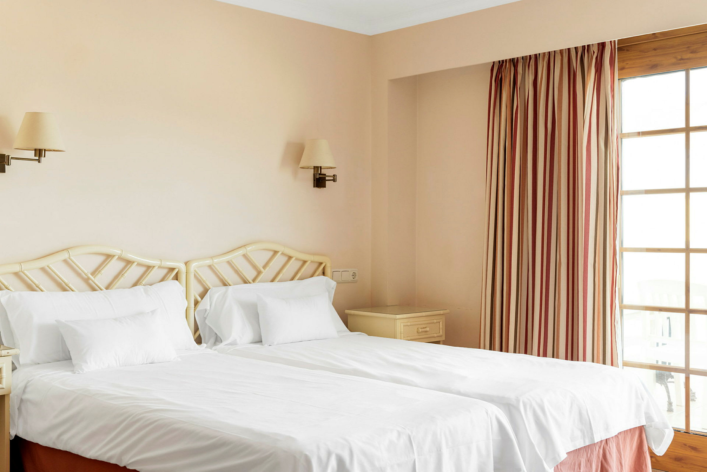 To enkeltsenger med hvitt sengetøy på et hotellrom. (AI-generert tekst)