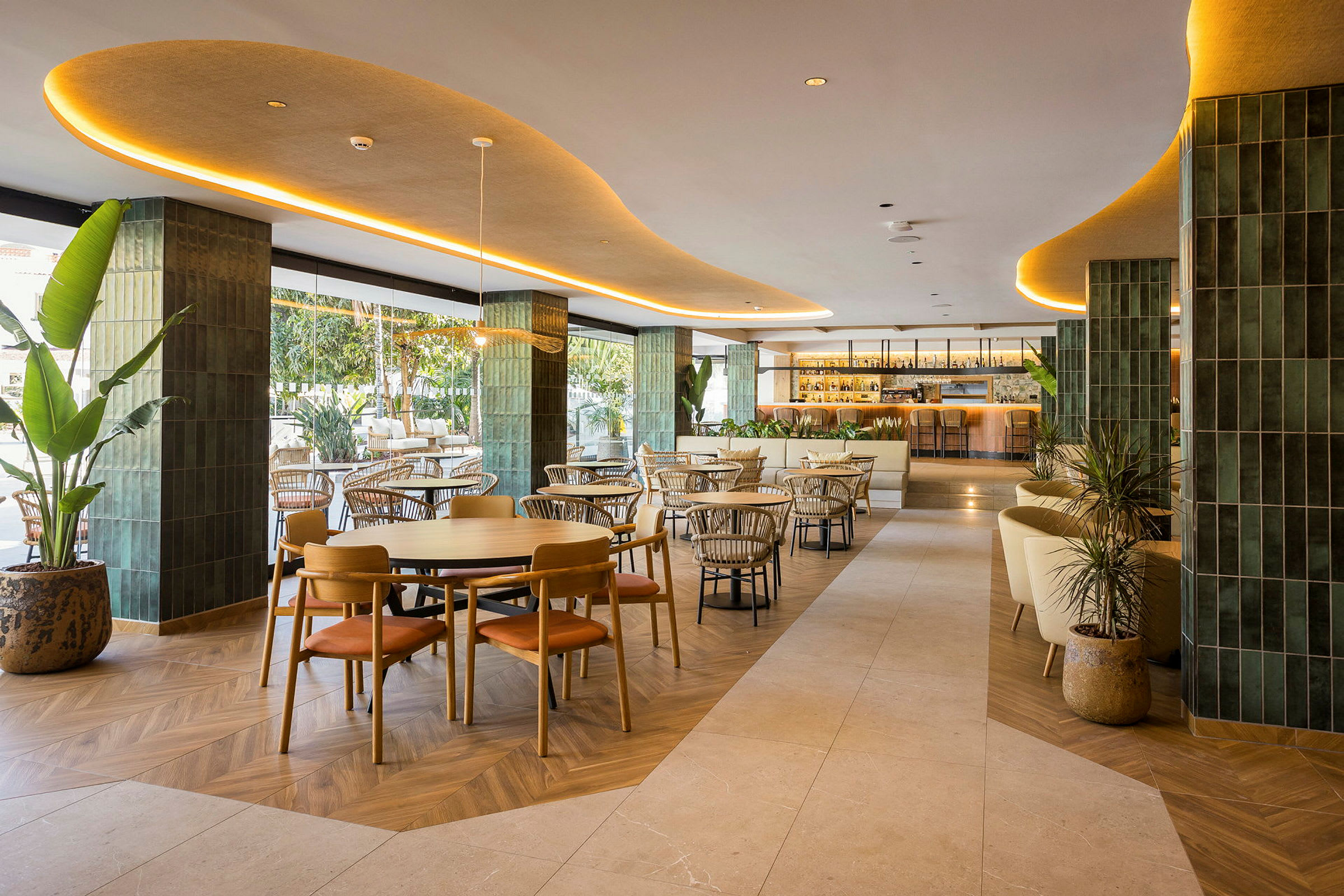 En elegant restaurant med moderne møbler og interiør, beliggende innendørs med grønne detaljer og stor bar i bakgrunnen. (AI-generert tekst)