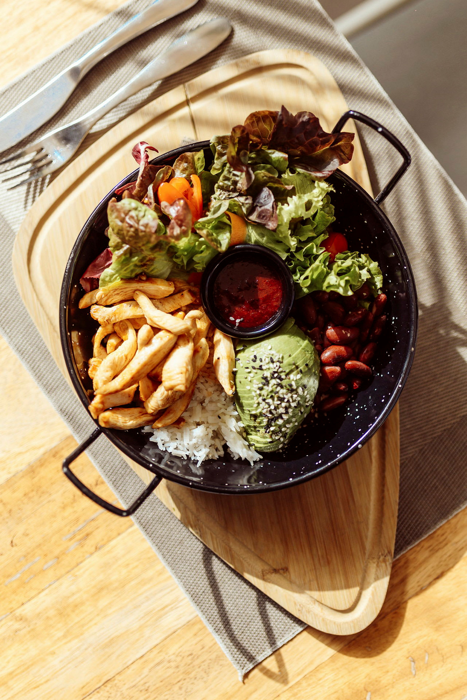 En matporsjon med kylling, ris, avokado, bønner, salat og saus. (AI-generert tekst)