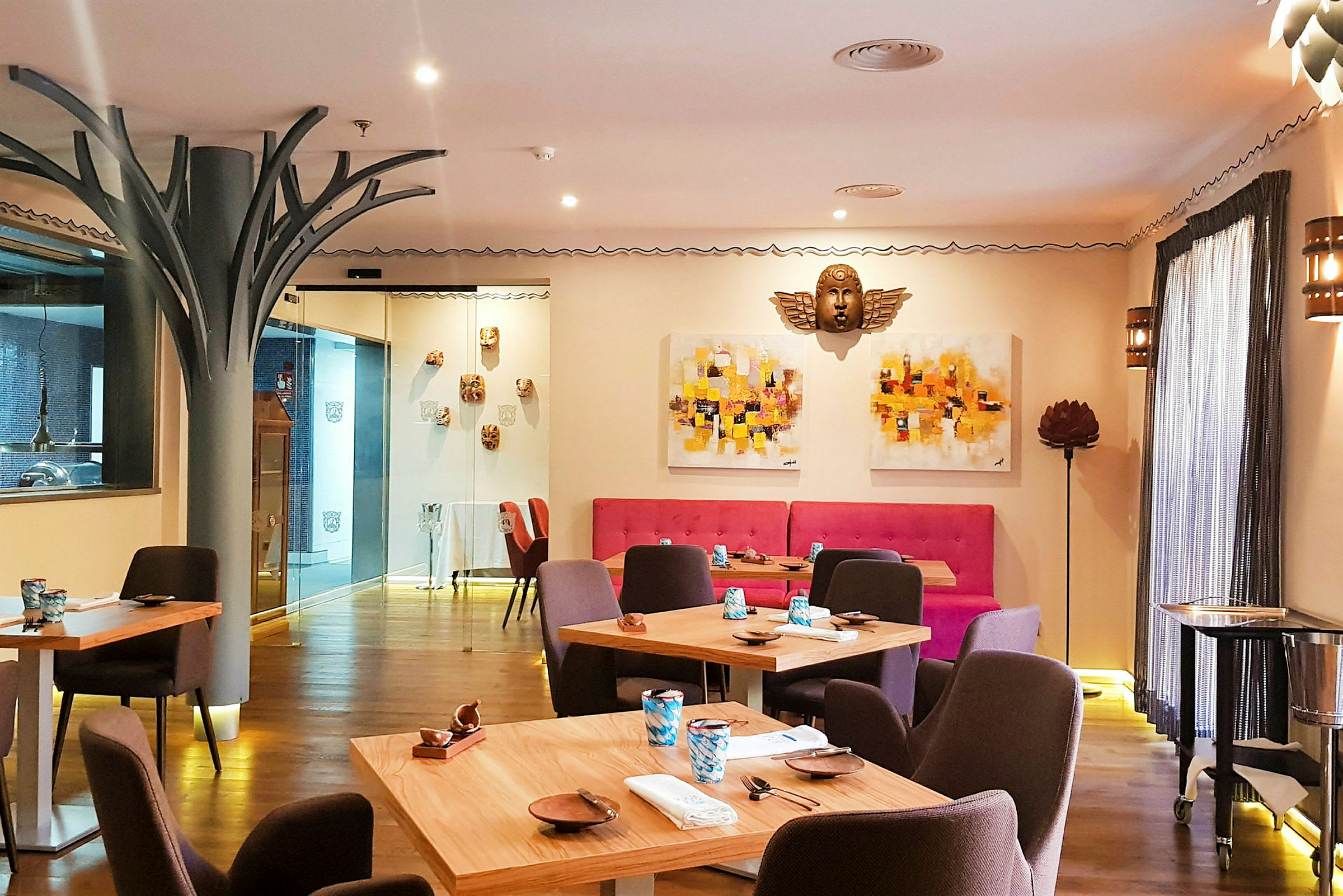 Bilde av en stilfullt innredet restaurant med trebord og fargerike veggdekorasjoner. (AI-generert tekst)