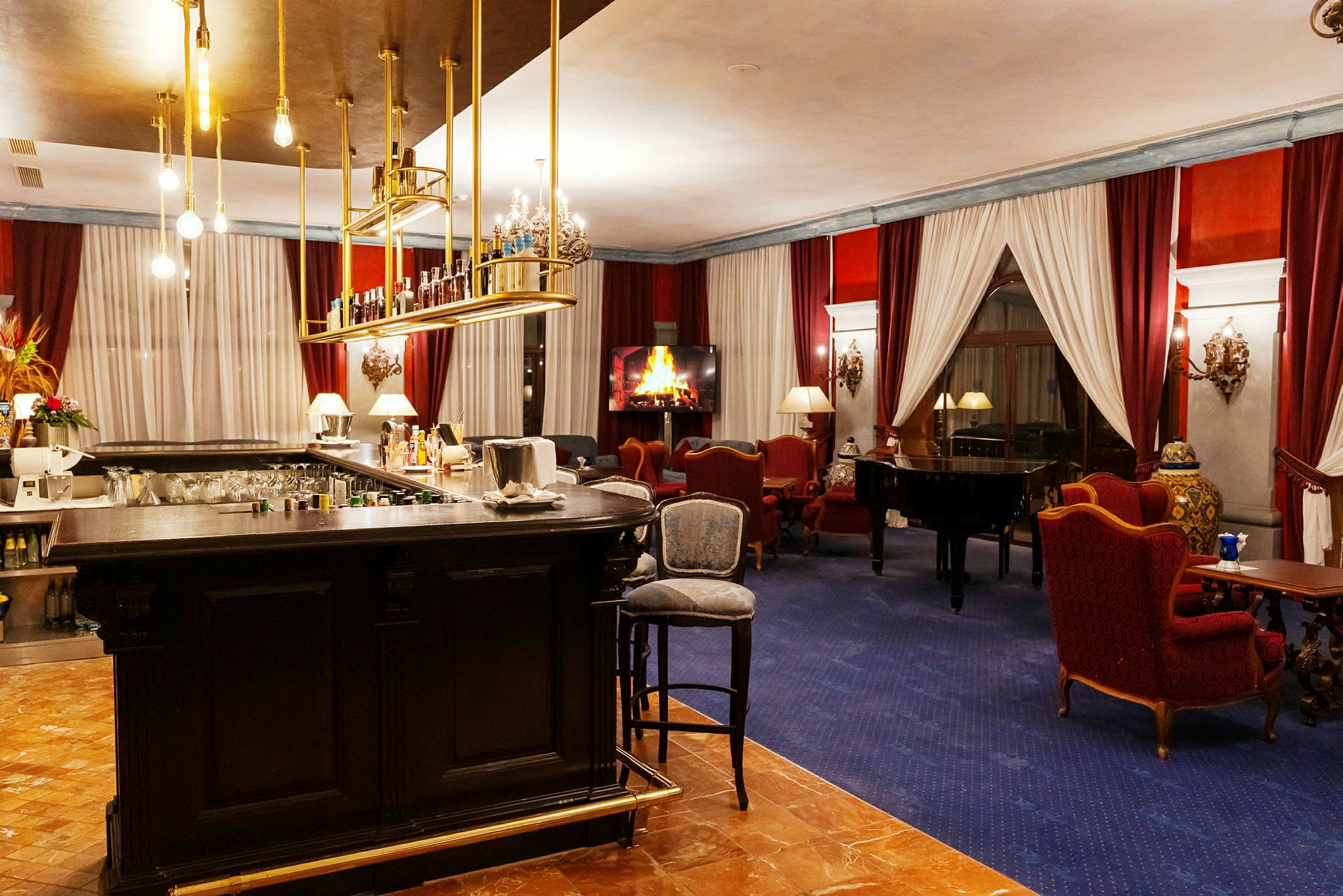 En elegant hotellounge med en bardisk, et piano og sittegrupper foran en digital peis. (AI-generert tekst)