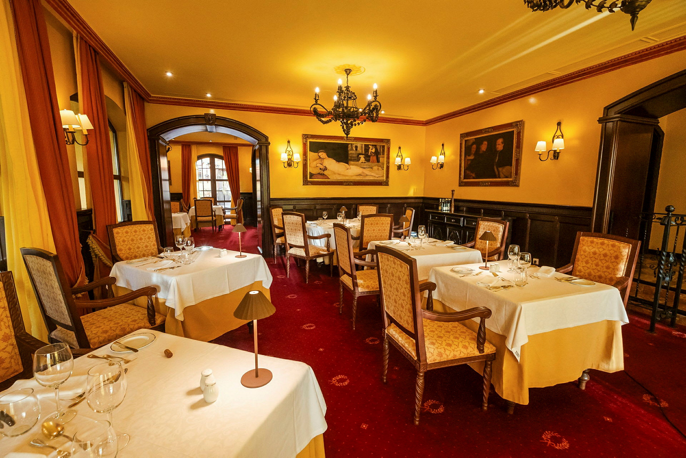 En elegant restaurant med dekket bord, myk belysning og kunstverk på veggene. (AI-generert tekst)