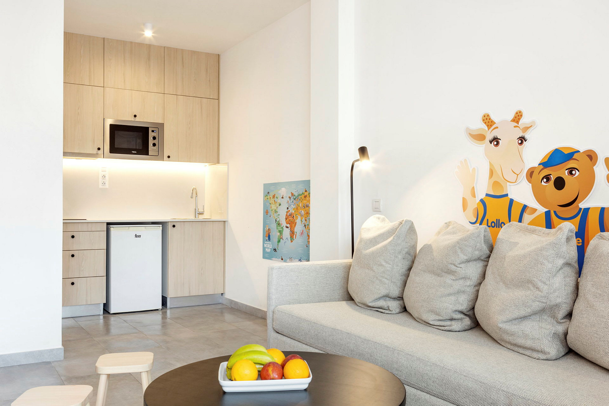 Bilde av et lite kjøkken med tremøbler, sofa med grå puter, samt dekorasjon med giraff- og bjørnefigurer på veggen. (AI-generert tekst)