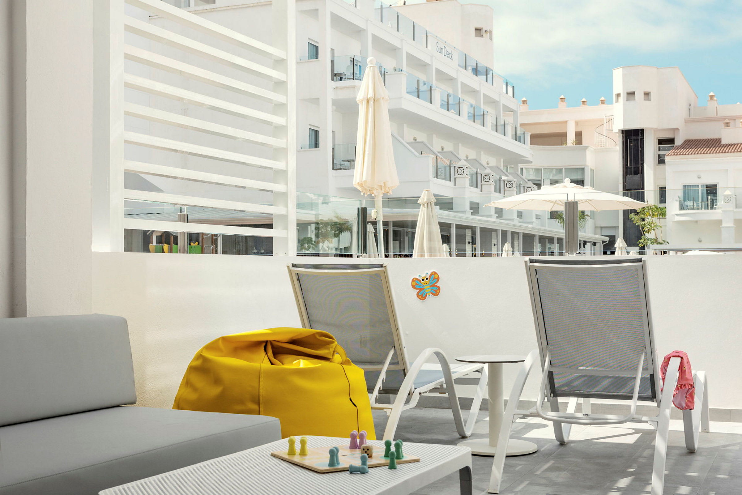 Bilde av en hotelltakterrasse med sittemøbler og utsikt over bygninger. (AI-generert tekst)