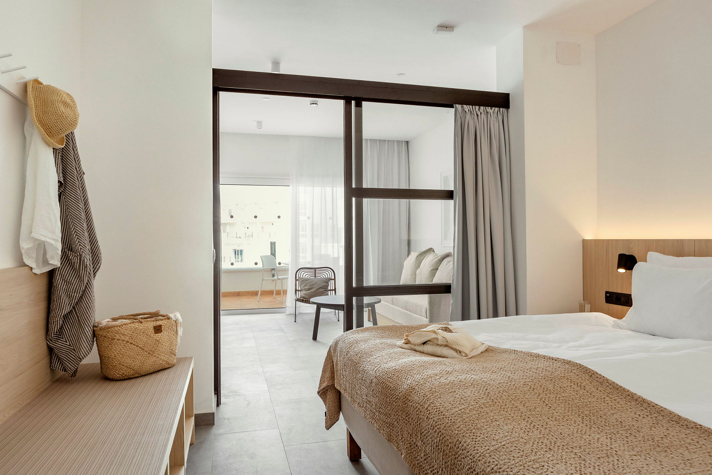 Et hotellrom med en seng og sittegruppe adskilt av en glassvegg. (AI-generert tekst)