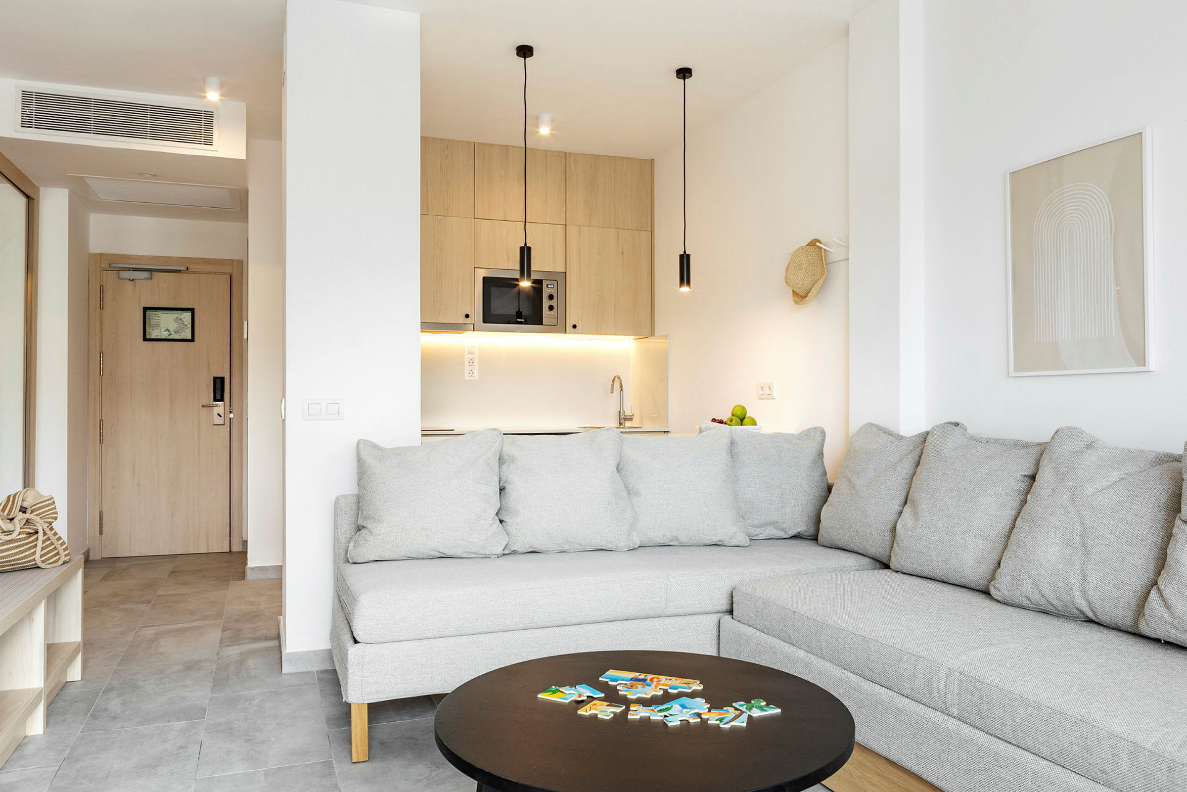En moderne leilighet med grå sofa og et åpent kjøkkenområde. (AI-generert tekst)
