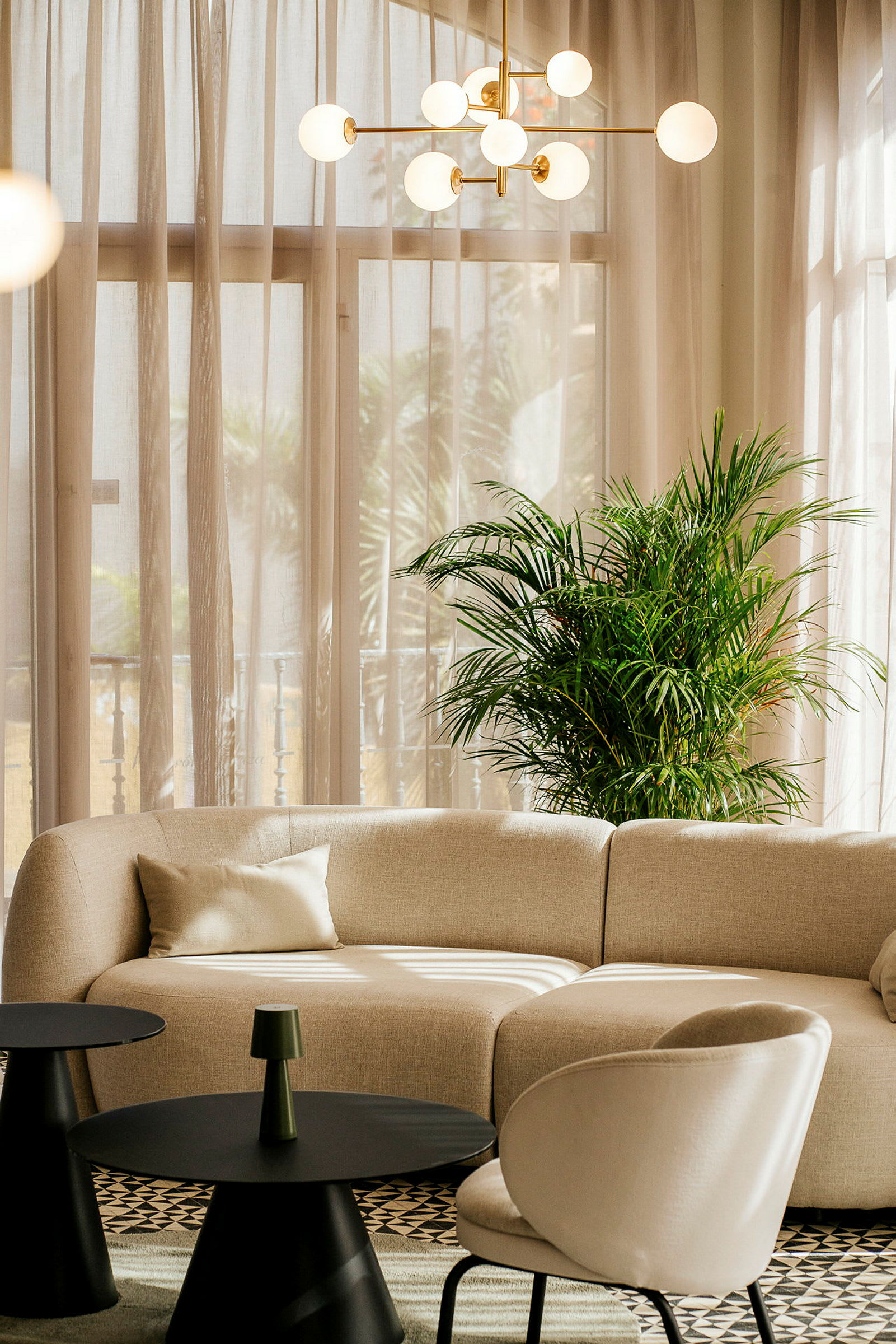 En sofagruppe med beige sofa, grønn plante og runde bord. (AI-generert tekst)
