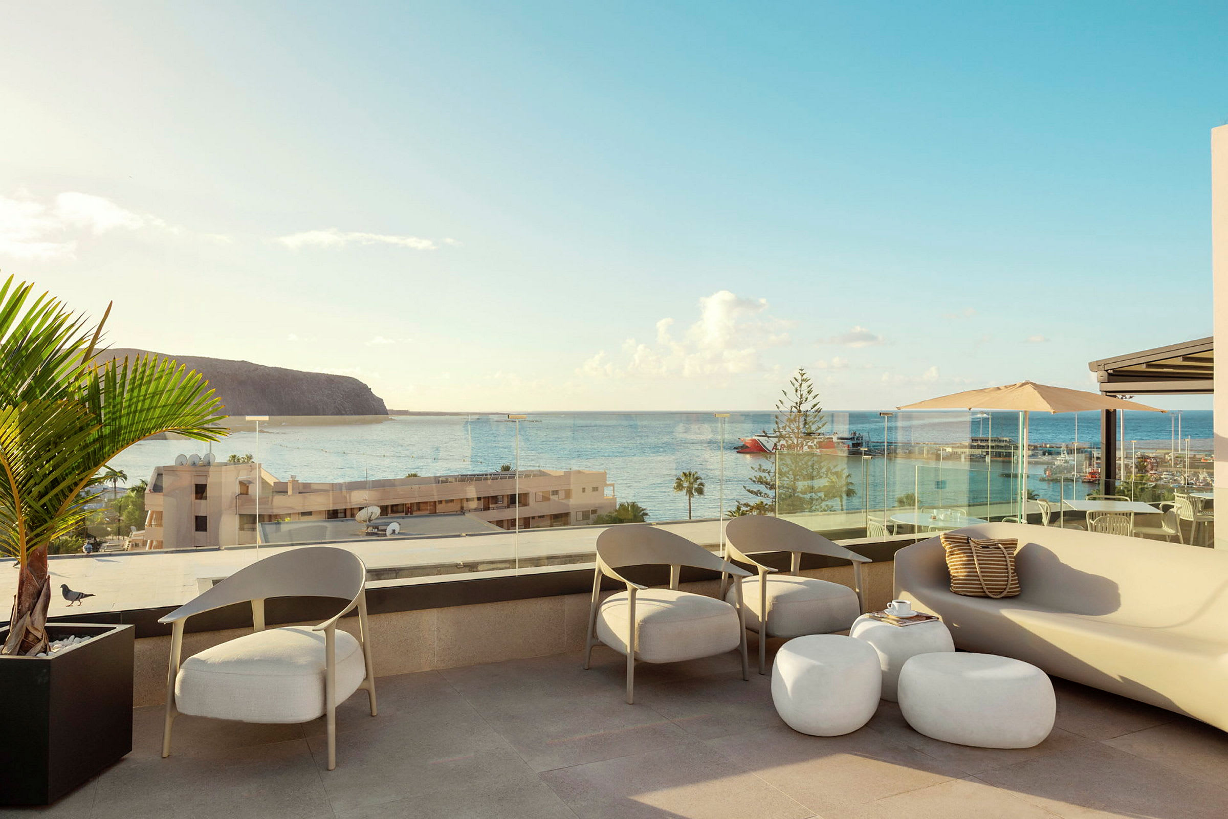 En terrasse med sitteplasser og utsikt over havet og en havn. (AI-generert tekst)