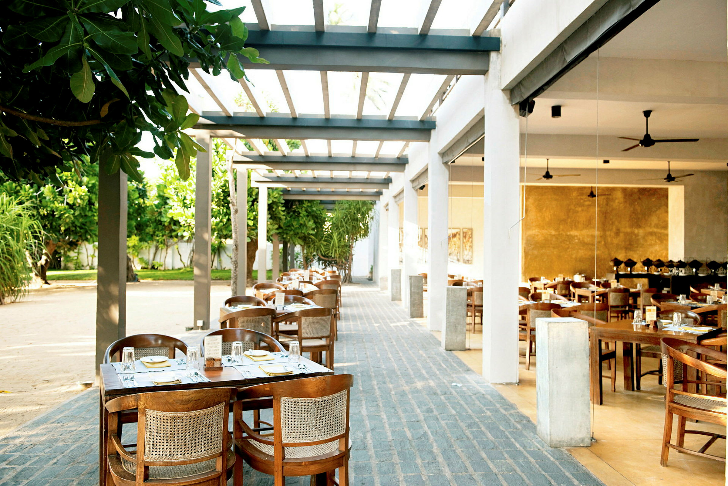 Uterestaurant med bord og stoler arrangert under en pergola. (AI-generert tekst)