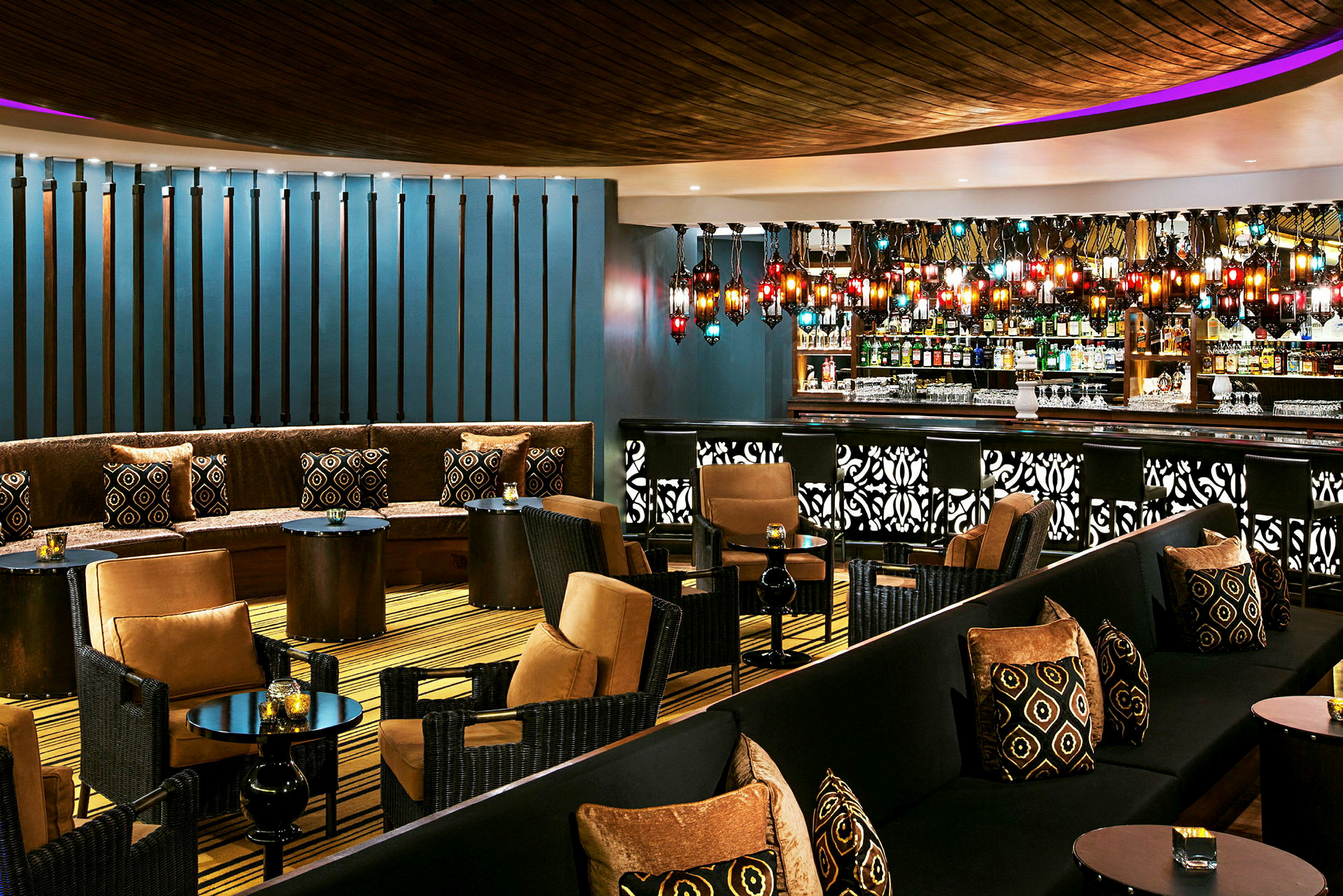 En elegant lounge med sitteplasser, små bord og en bar. Fargerik belysning og detaljer pynter interiøret. (AI-generert tekst)