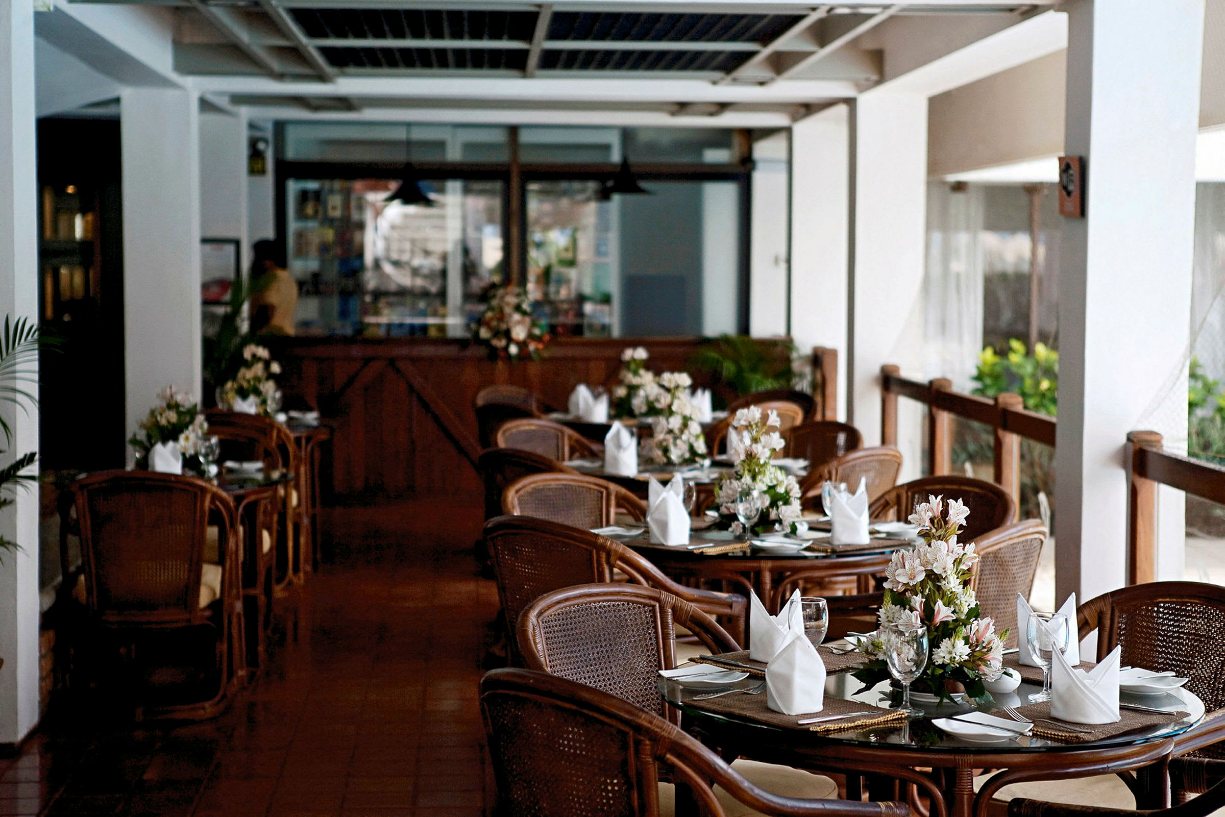 En restaurant med dekkede bord og blomster på hvert bord. (AI-generert tekst)