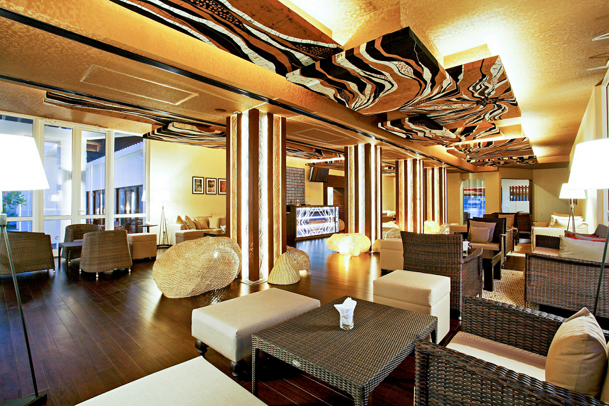 En elegant lounge med moderne interiør, rottingmøbler, bord og belysning pryder rommet. (AI-generert tekst)
