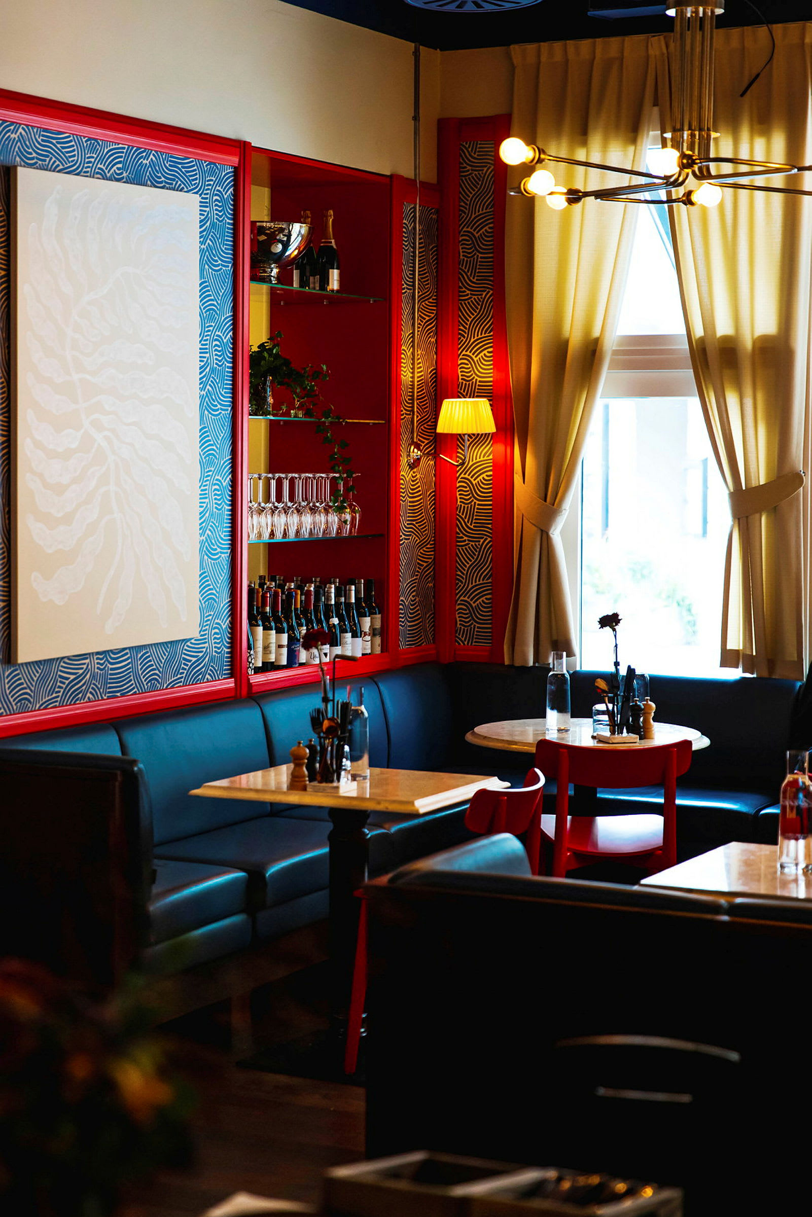 En restaurant med elegant interiør, røde og blå vegger, samt bord med sitteplasser. (AI-generert tekst)