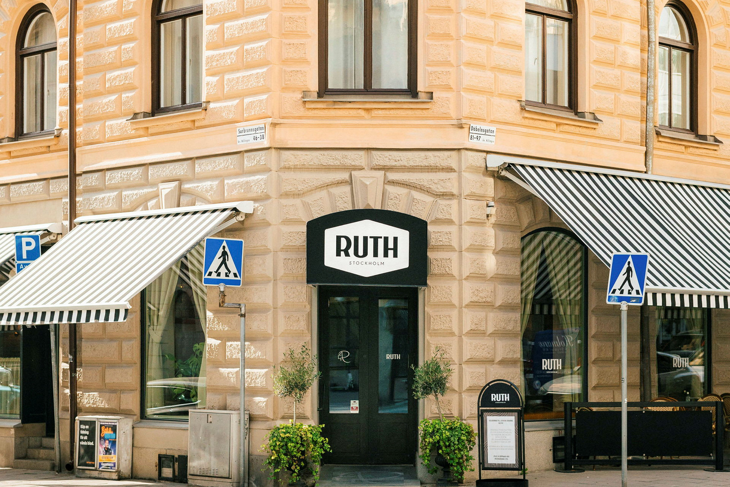 Fasaden til en bygning med store vinduer og markiser, med inngangen til "Ruth Stockholm" som har et skilt over døren. (AI-generert tekst)
