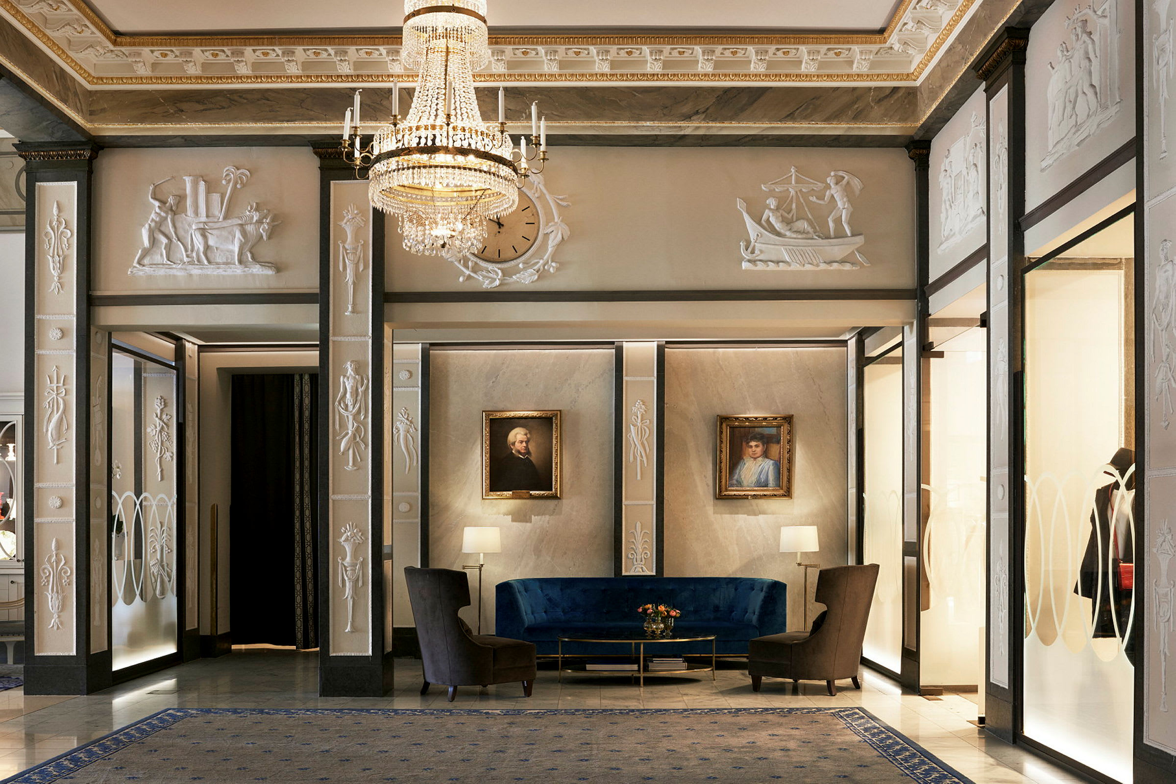En elegant hotellobby med et blått sitteområde, veggrelieffer og malerier. (AI-generert tekst)