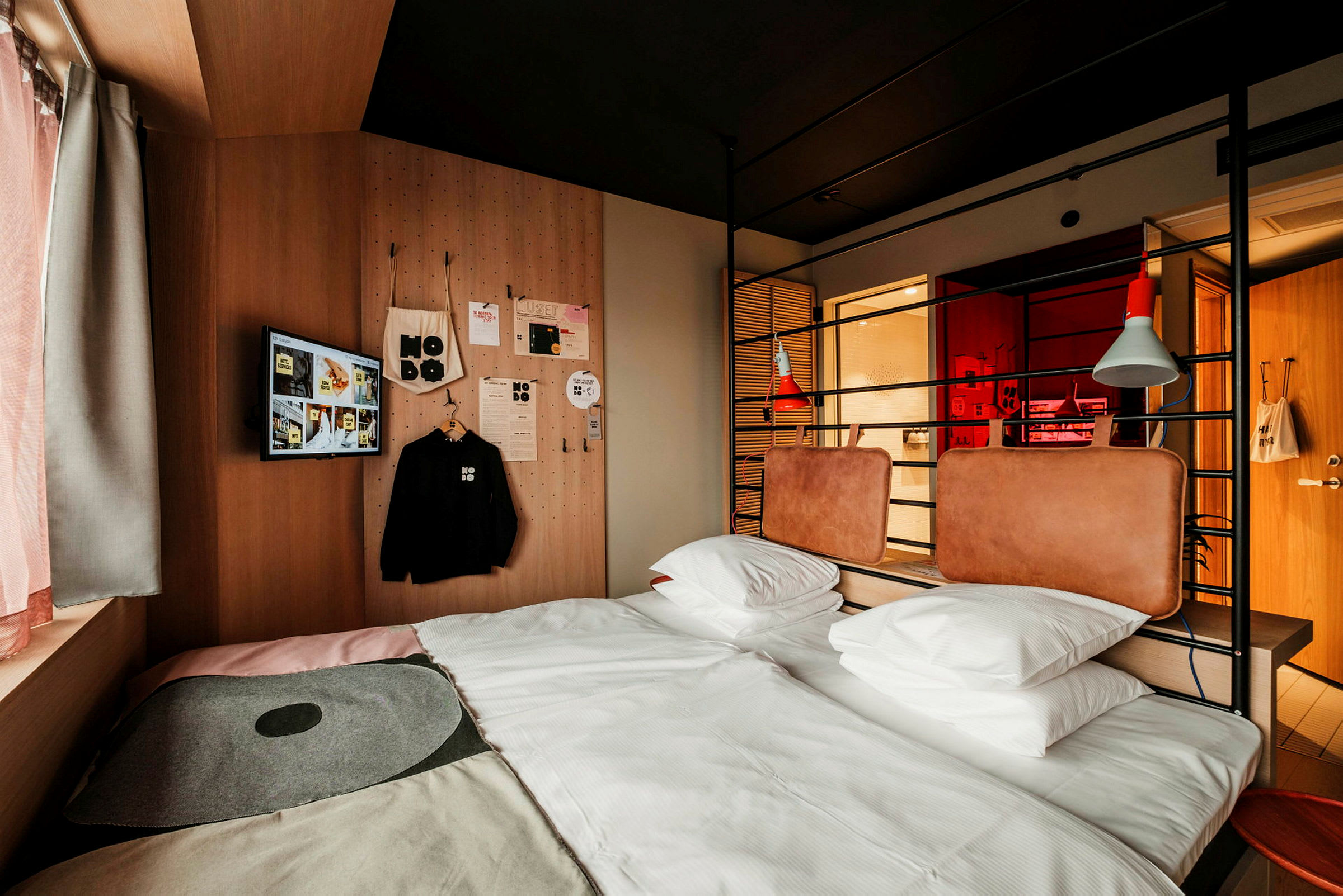 Et moderne hotellrom med en seng, to puter og enkle designelementer som veggdekorasjoner og fremtredende farger. (AI-generert tekst)