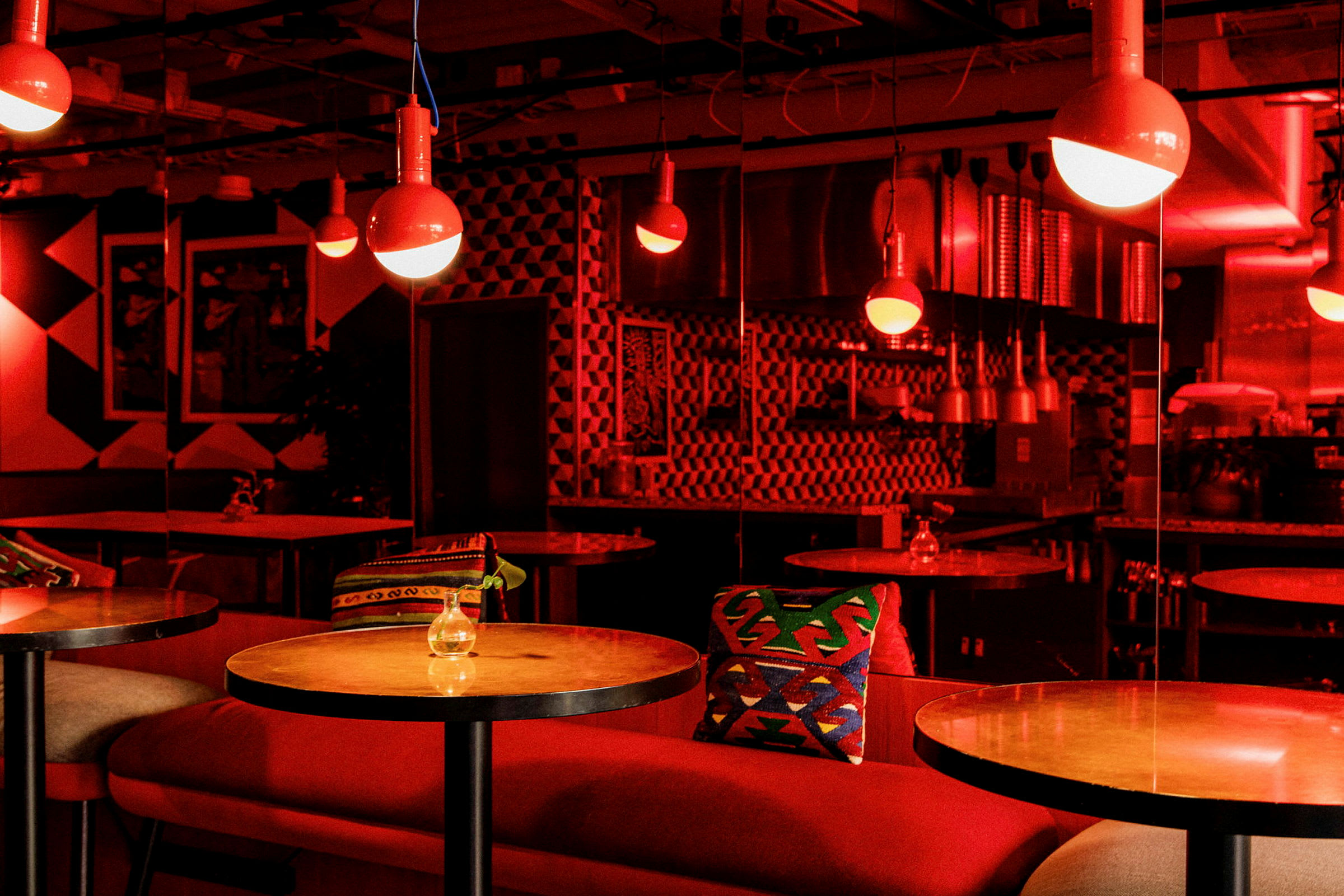 Innredning av en moderne restaurant med røde bordlamper og fargerike puter. (AI-generert tekst)
