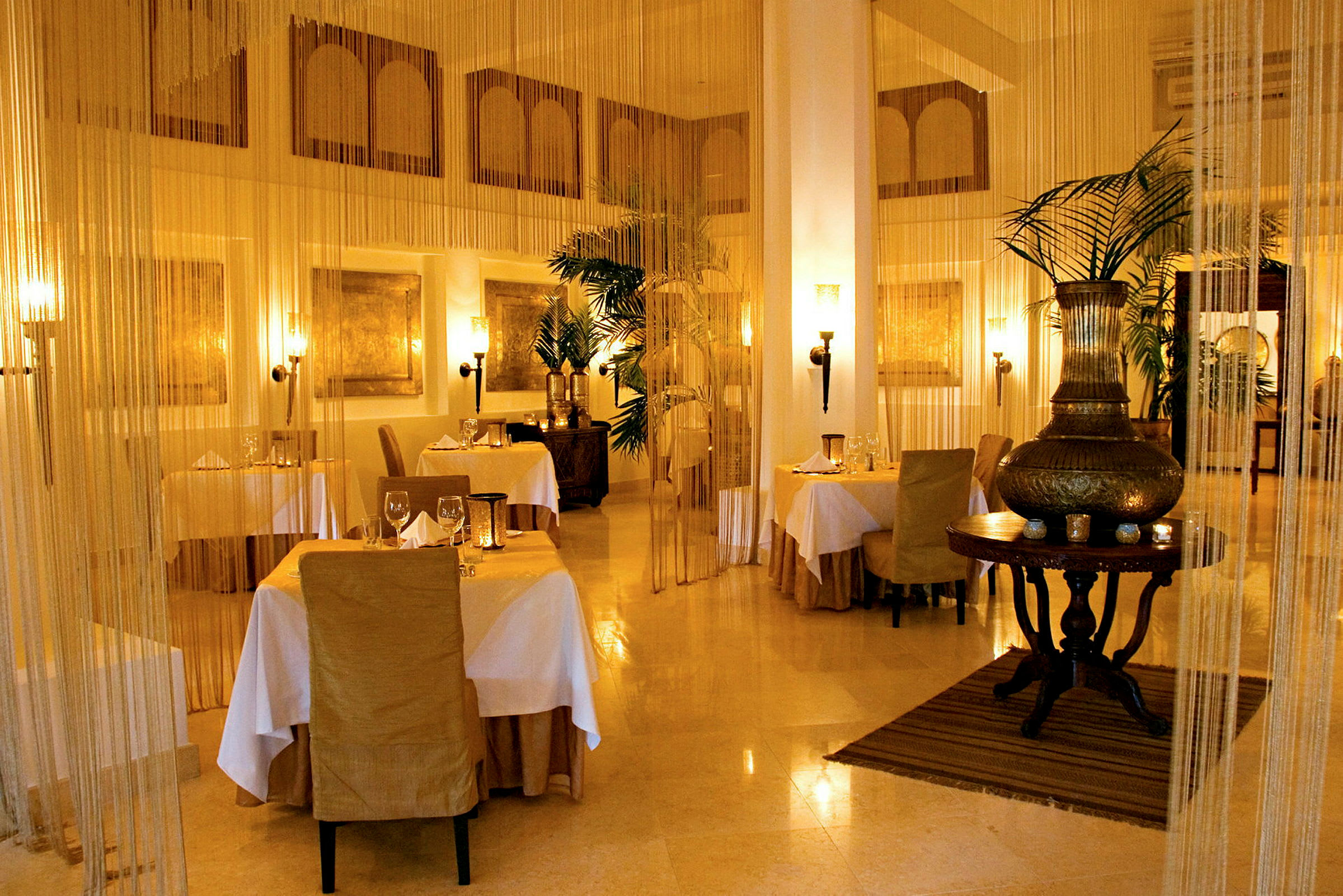 En elegant restaurant med dekkede bord, stoler i beige og myk belysning. (AI-generert tekst)