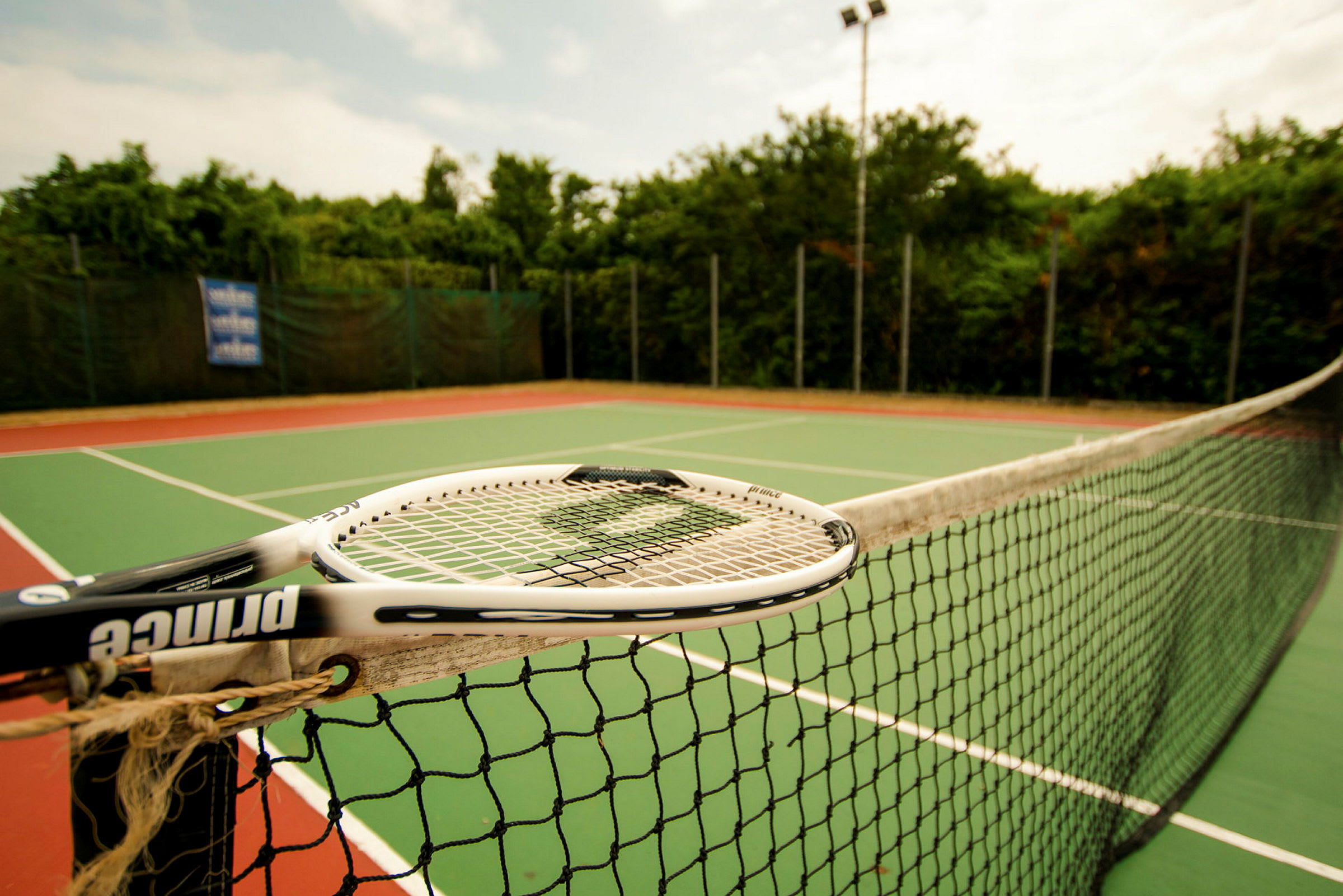 En tennisbane med nett og racket. (AI-generert tekst)