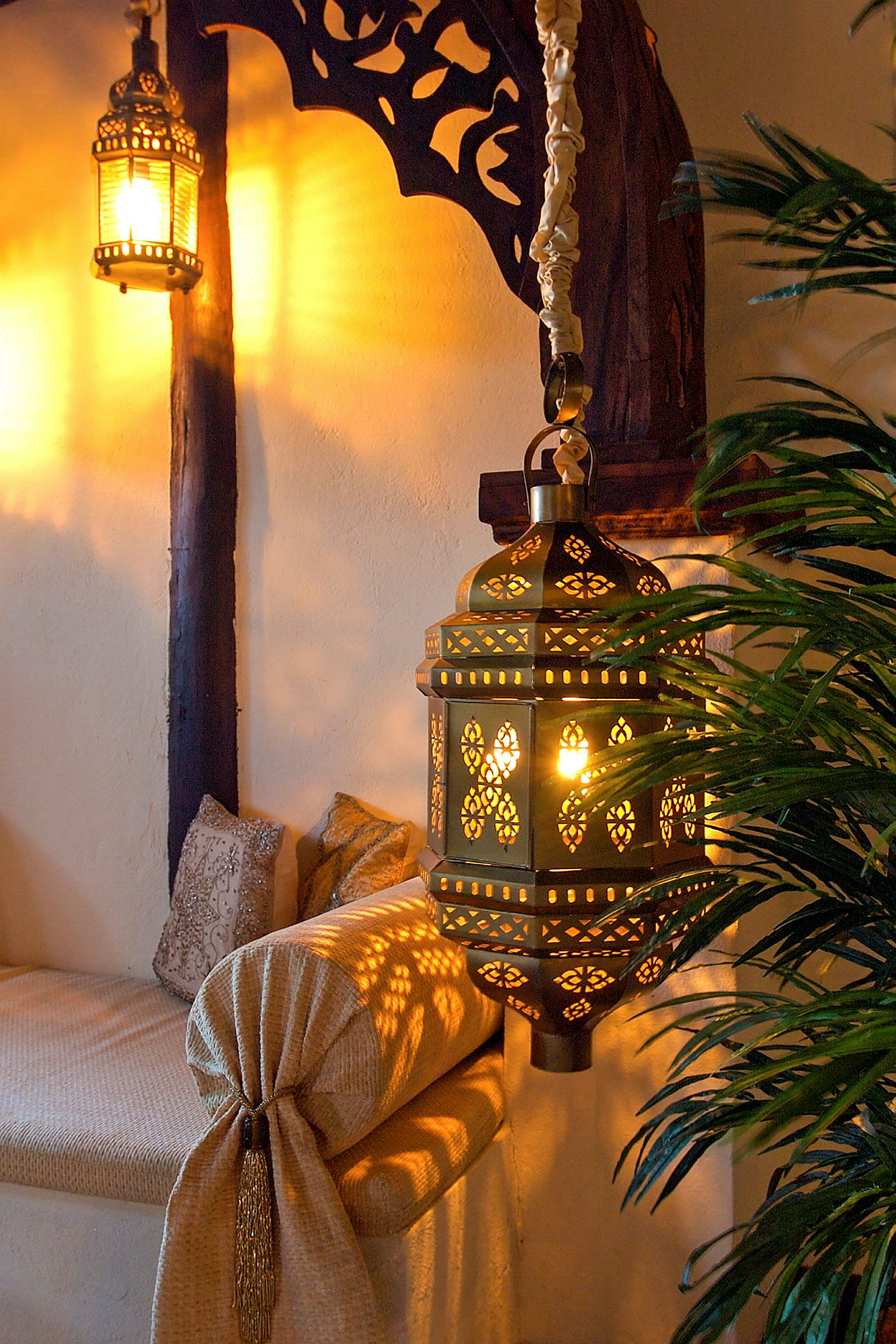 En opplyst orientalsk inspirert lampe henger i interiør med dekorative detaljer inkludert en forheng. (AI-generert tekst)