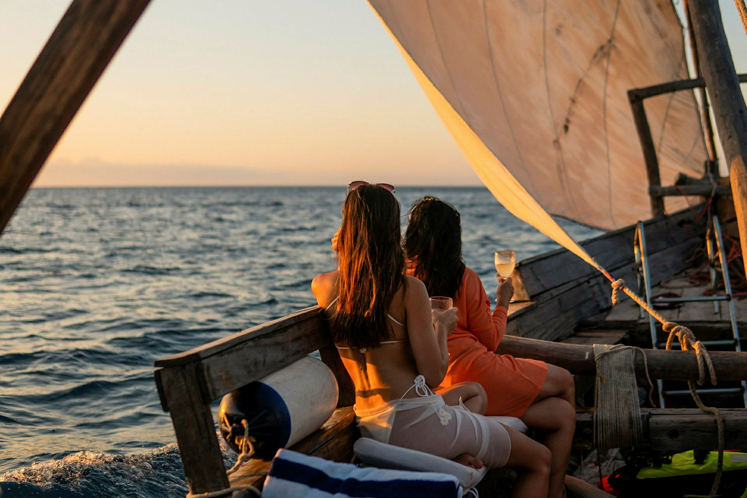 To personer sitter på en seilbåt med drinker i hånden og ser ut over havet. (AI-generert tekst)