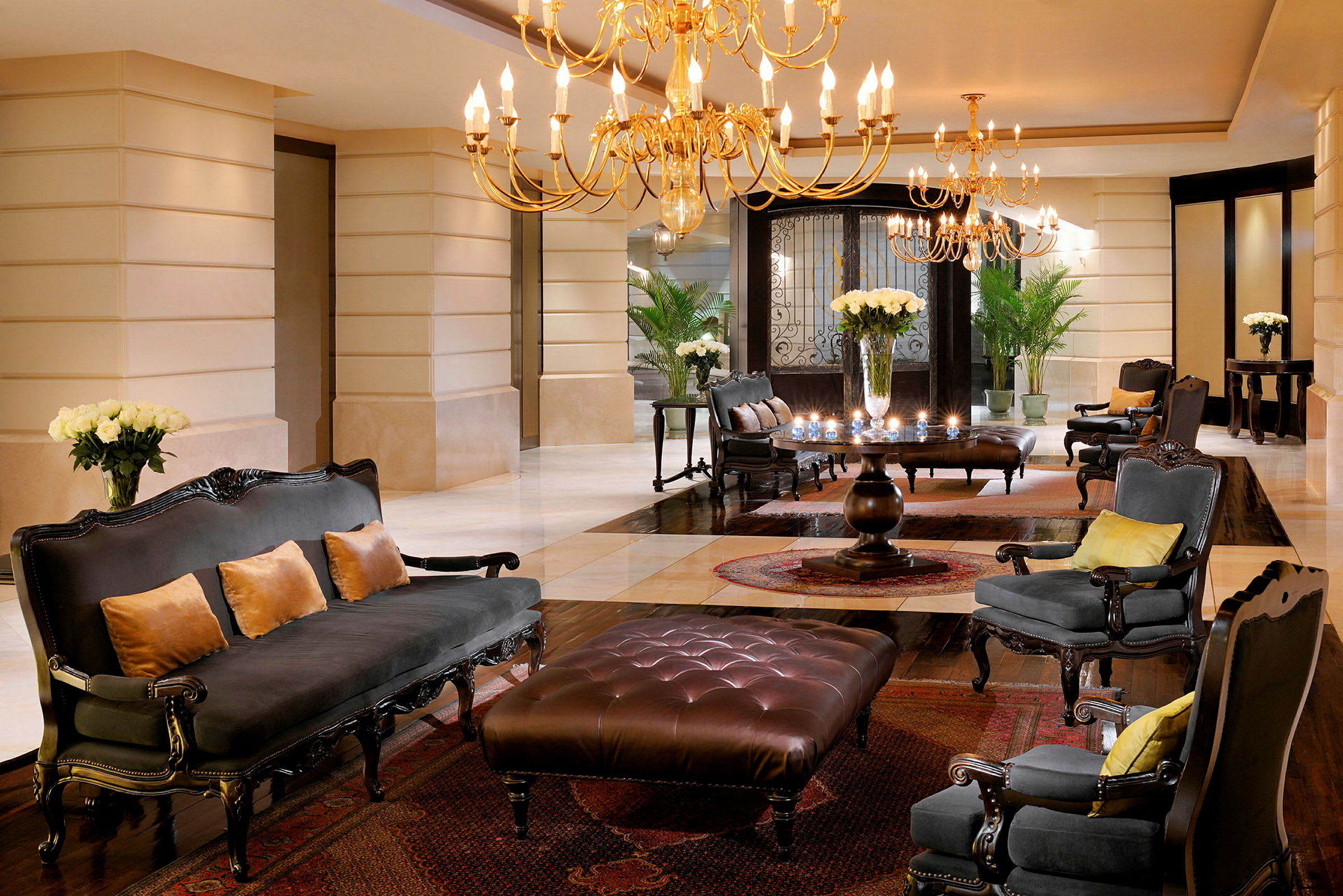 En elegant hotellobby med lysekroner, komfortable sittemøbler og blomster plassert på bord. (AI-generert tekst)