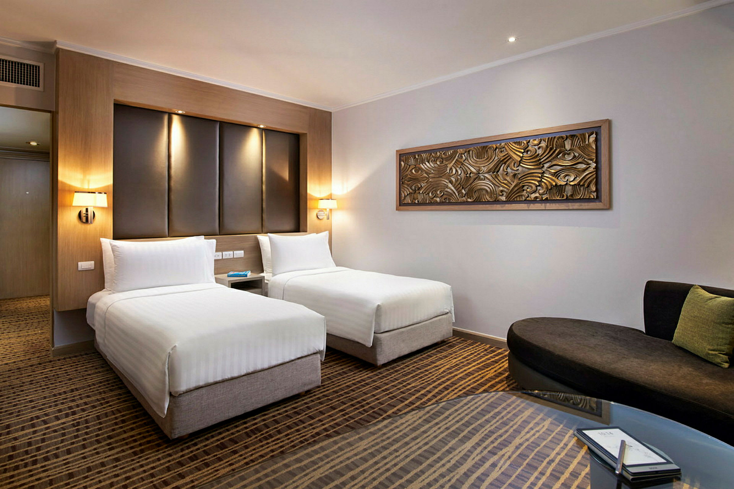 Moderne hotellrom med to enkeltsenger, en sofa og et bord. (AI-generert tekst)