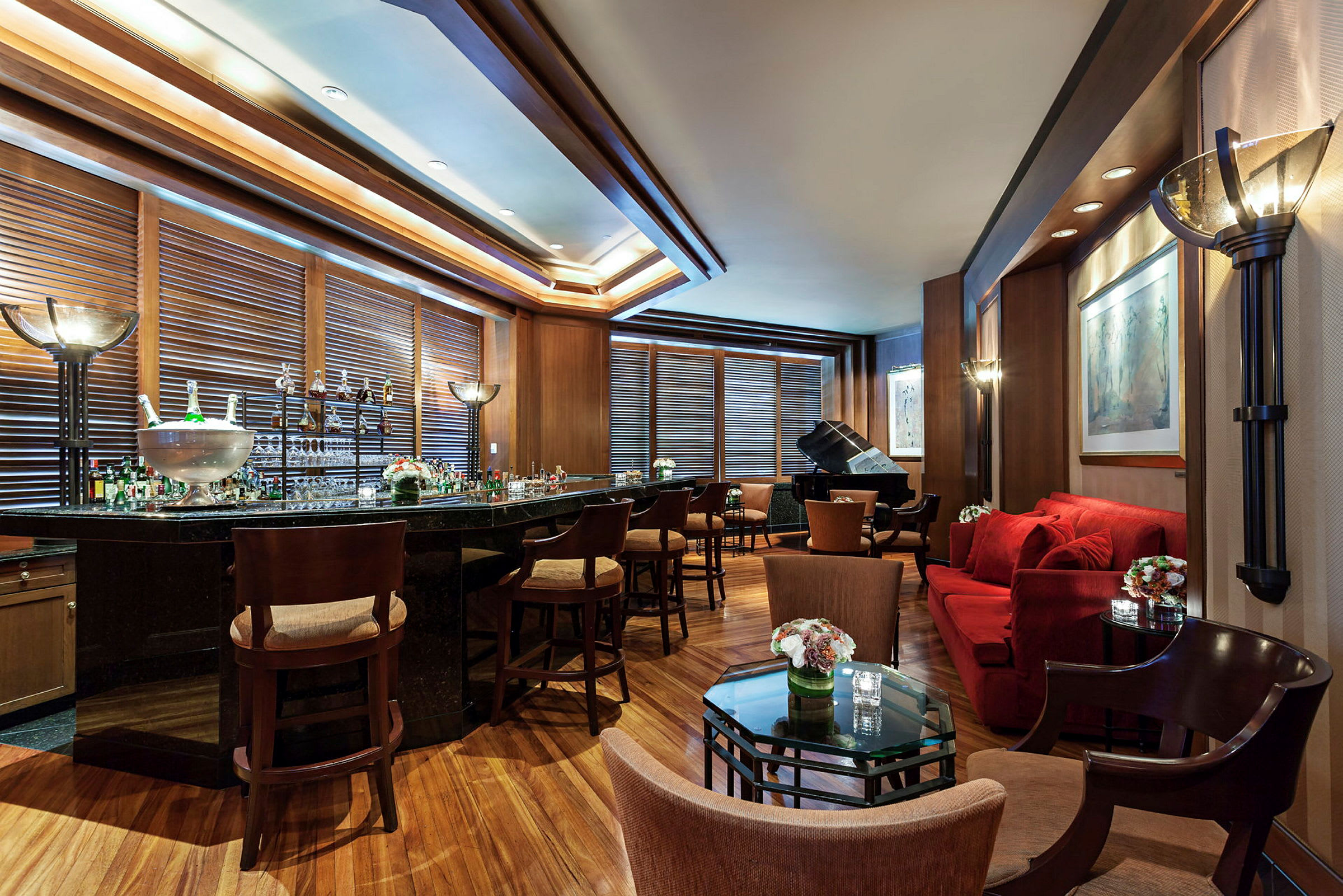 Et elegant innredet loungeområde med en innbydende bar, komfortable sitteplasser og et piano i bakgrunnen. (AI-generert tekst)