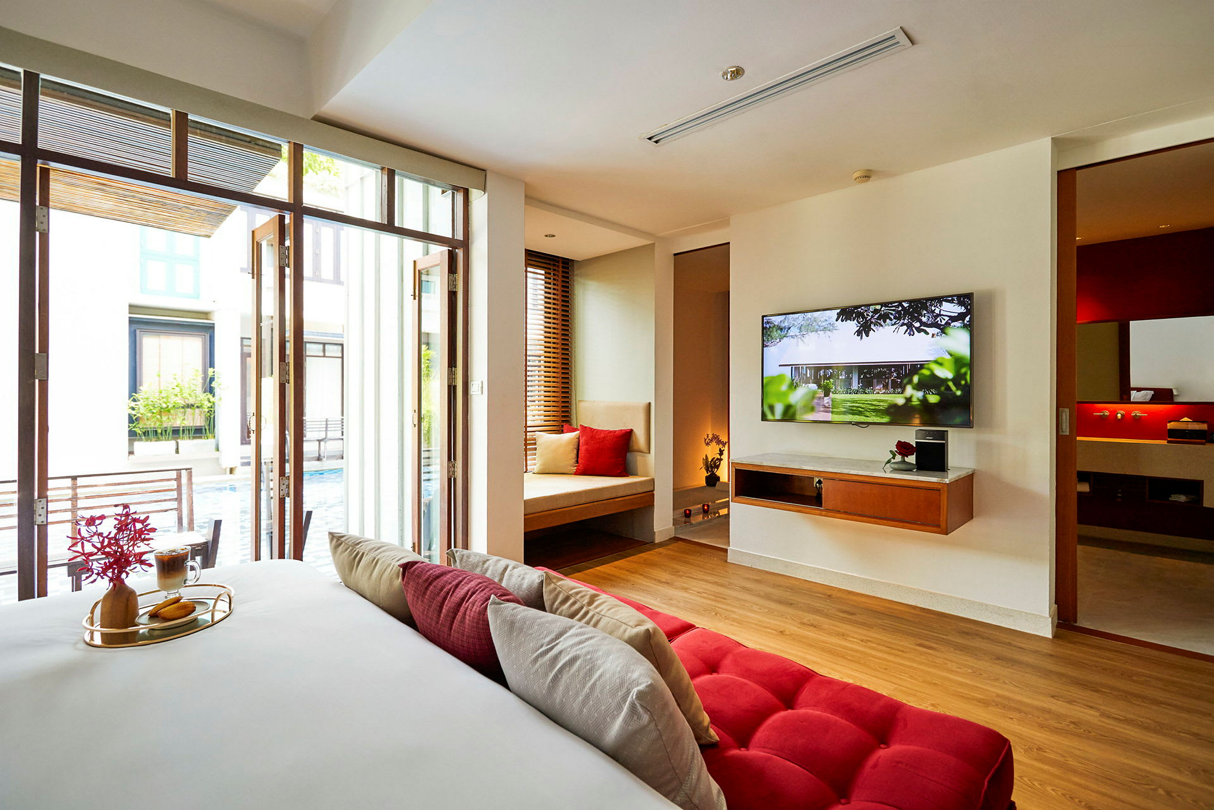 Et hotellrom med moderne innredning, en stor TV og utsikt mot et basseng. (AI-generert tekst)