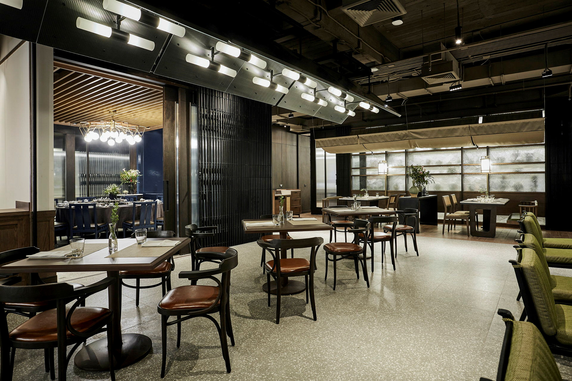 En moderne og elegant restaurantmiljø med bord og stoler plassert i en luftig oppstilling. Designen inkluderer stilrene detaljer og myk belysning. (AI-generert tekst)