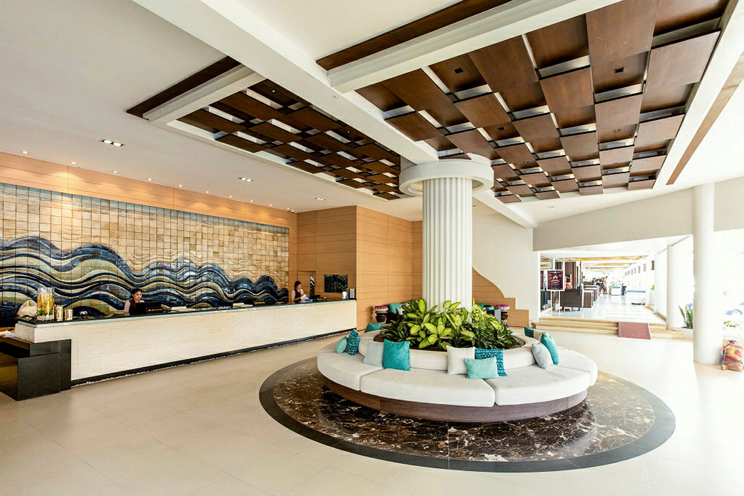 Hotellobby med resepsjonsdisk, en rund sittegruppe med planter i midten og dekorativ takdesign. (AI-generert tekst)