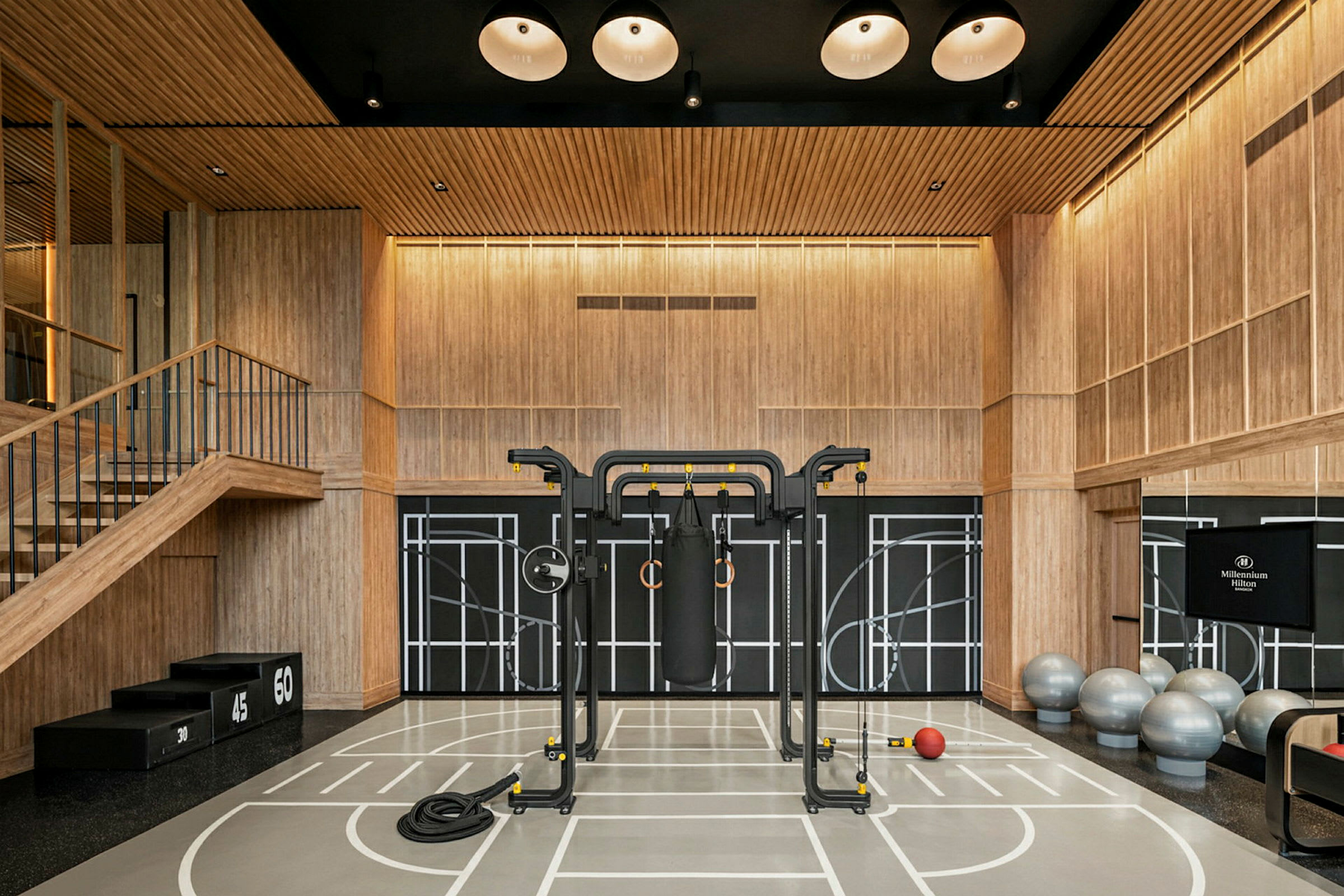 Et treningsstudio med trepaneler og treningsutstyr inkludert fitnessballer, en boksesekk og en stang. (AI-generert tekst)