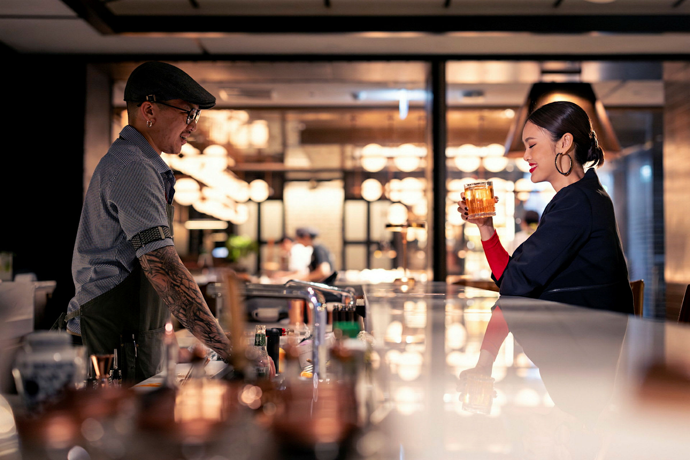 En bar med en bartender med hatt og en gjest som holder et glass drikke. (AI-generert tekst)