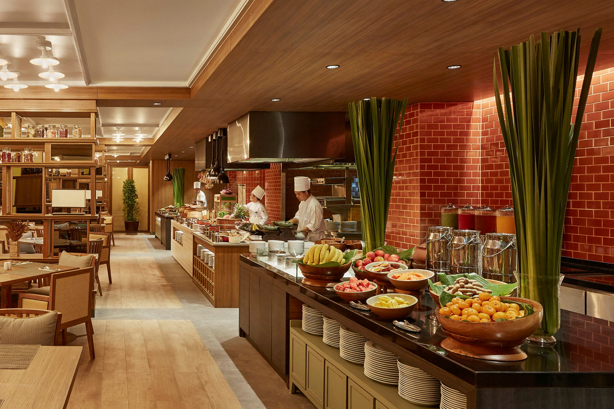 En restaurant med en oppstilt buffet som består av ulike frukter, retter og drikker. Kokker jobber bak buffeten. (AI-generert tekst)