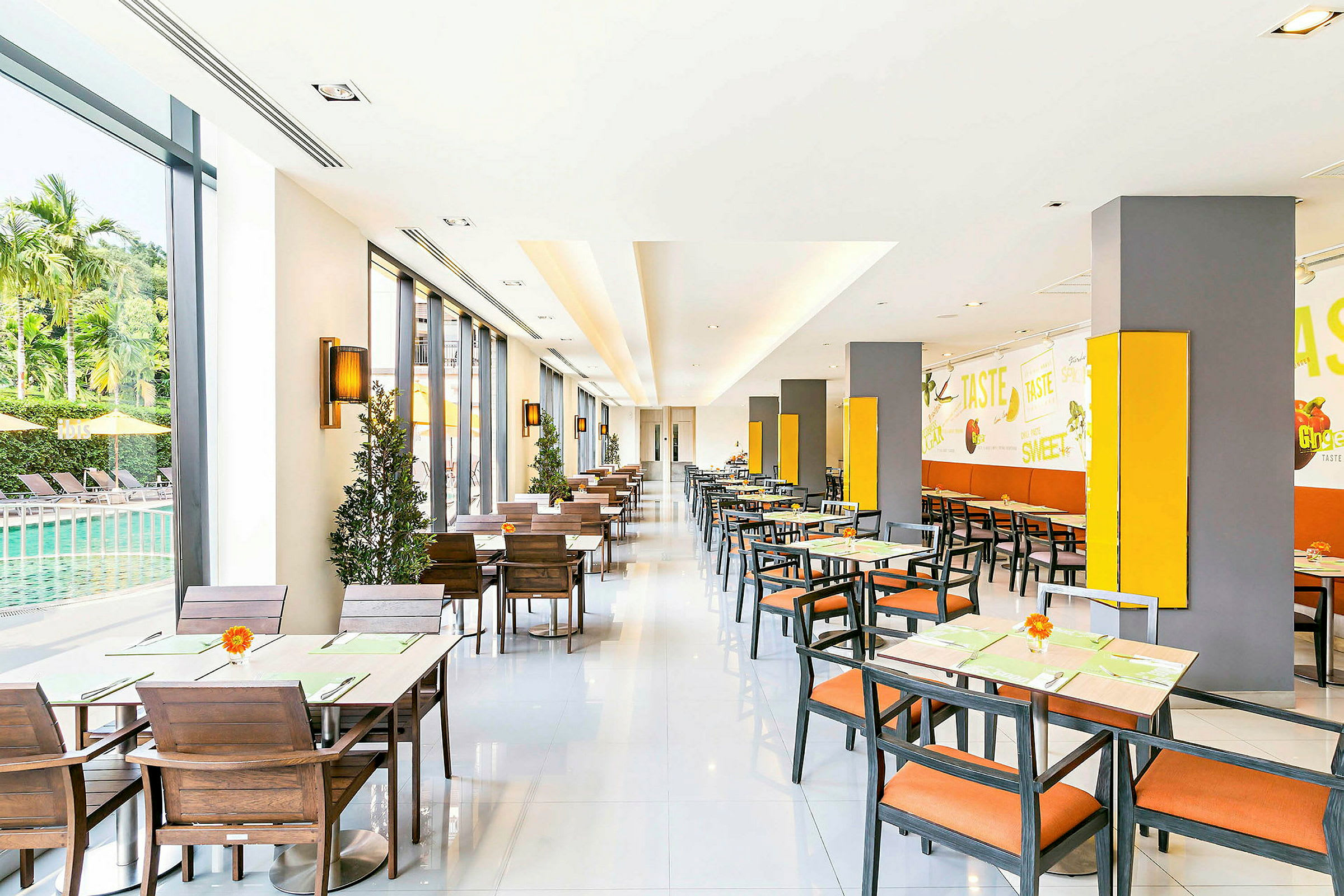 En lys restaurant med sitteplasser, vinduer mot et basseng og veggdekorasjoner. (AI-generert tekst)