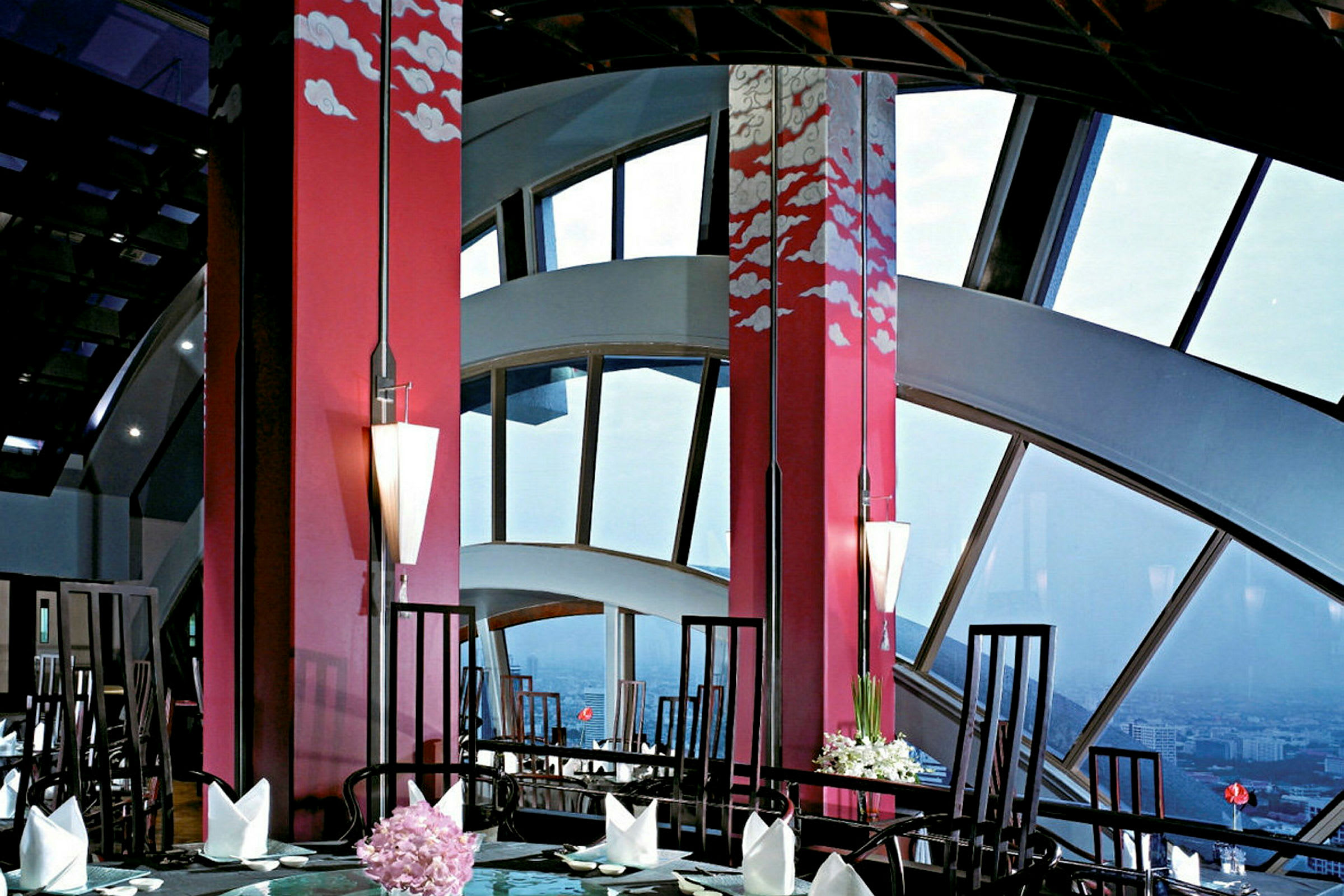 En elegant restaurant med store vinduer og rød innredning dekorert med kunstneriske skymotiver. (AI-generert tekst)