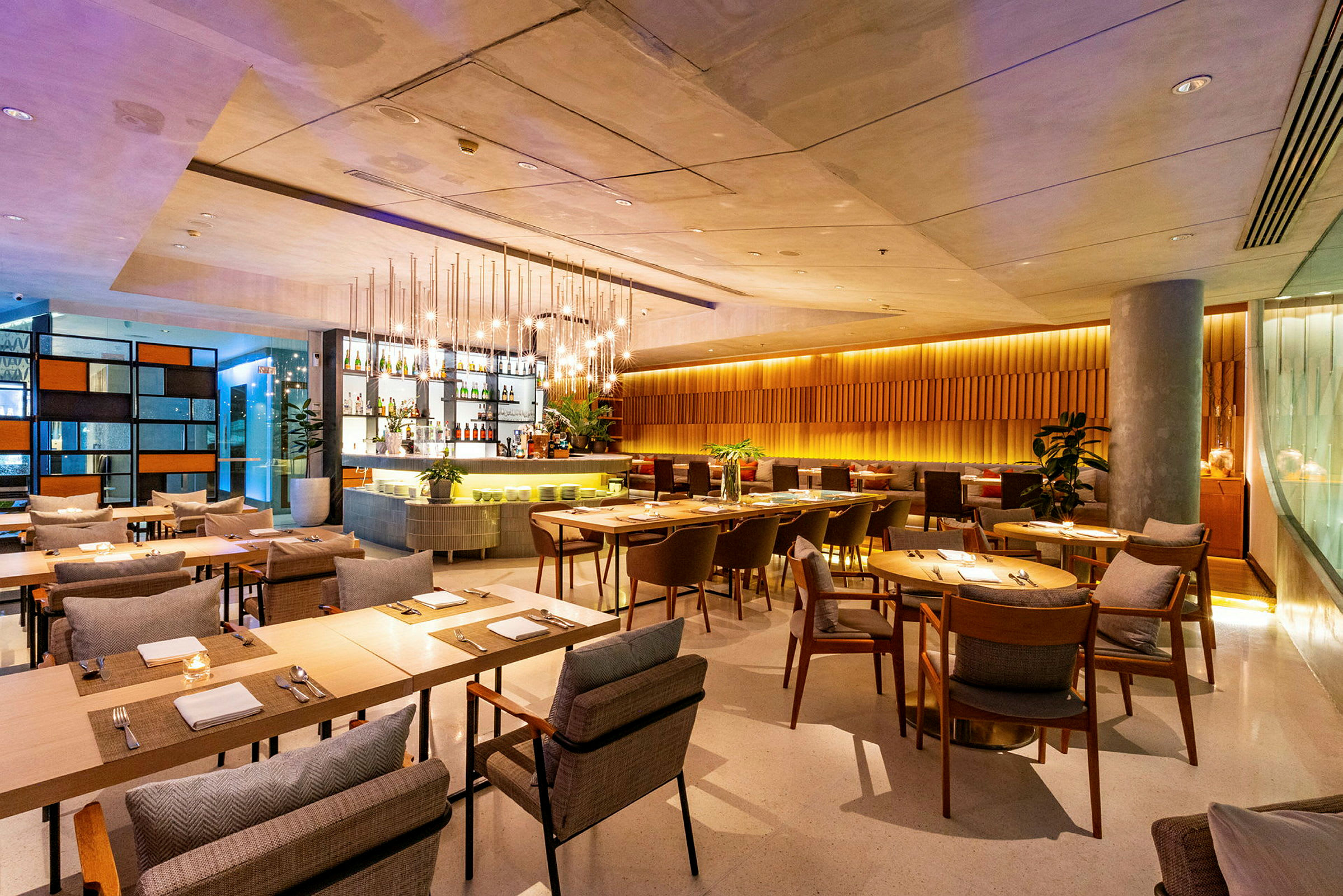 En moderne restaurant med trebord, komfortable stoler og en stilfull bar i bakgrunnen. (AI-generert tekst)