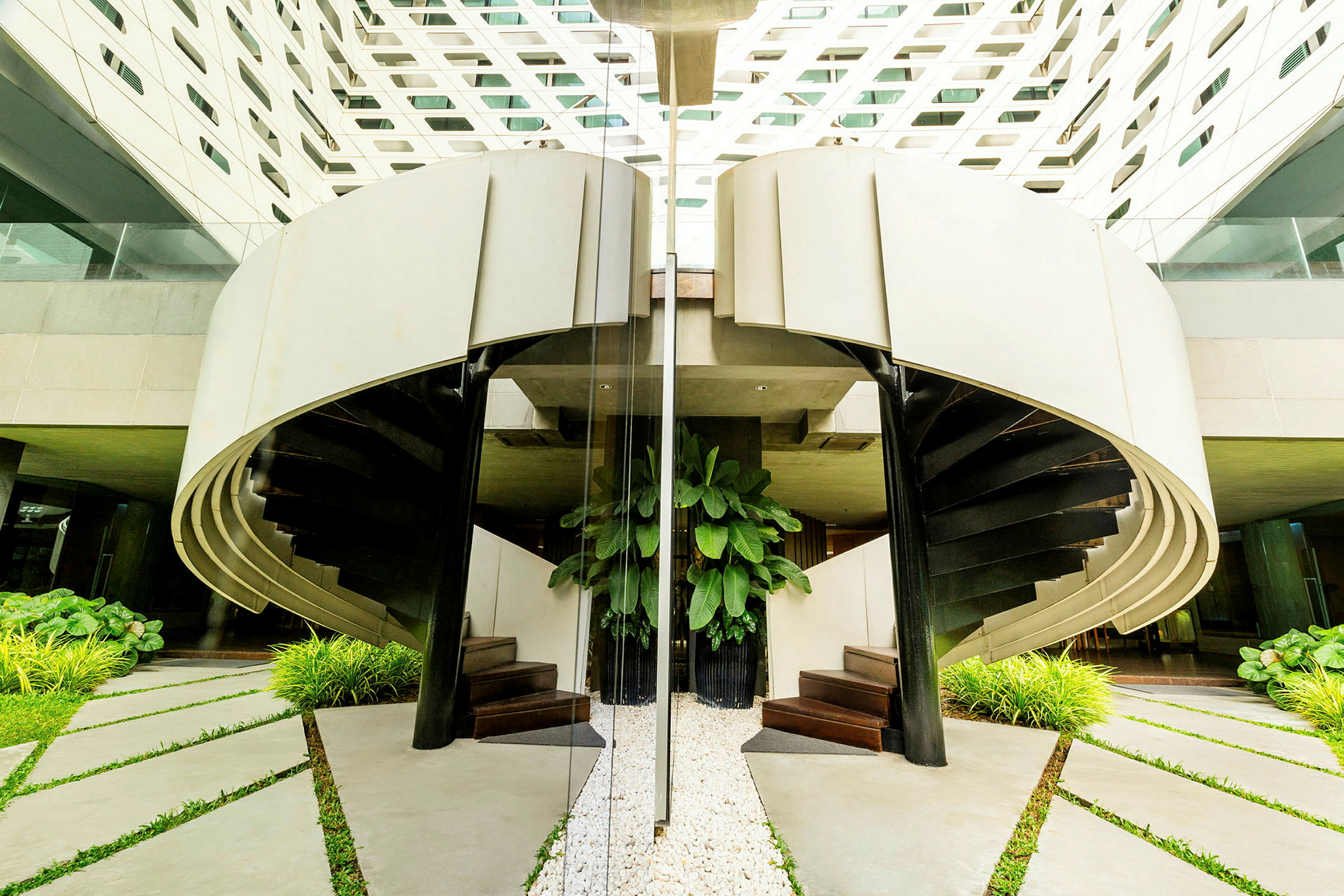 Bilde som viser en moderne spiraltrapp med planter og hvit arkitektur. (AI-generert tekst)